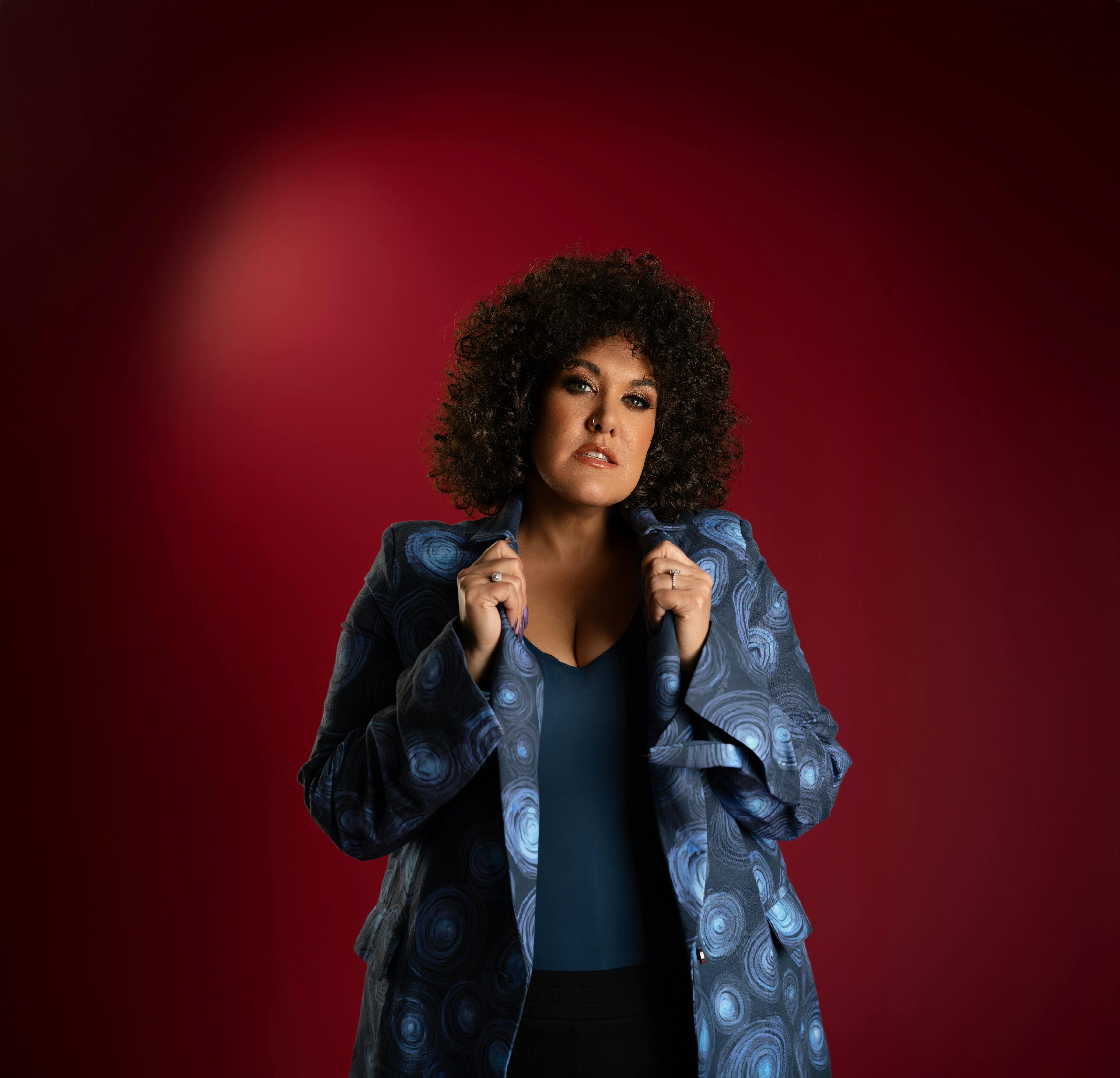 Casey with curly hair and hands on collar of shirt