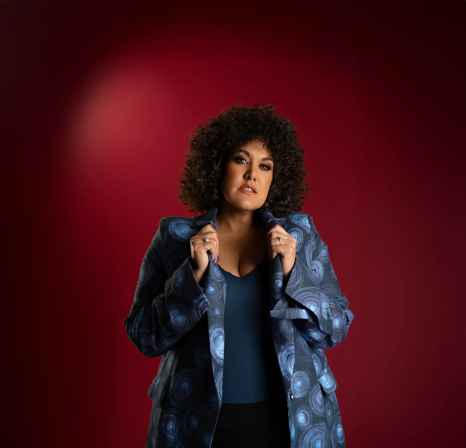 Casey with curly hair and hands on collar of shirt