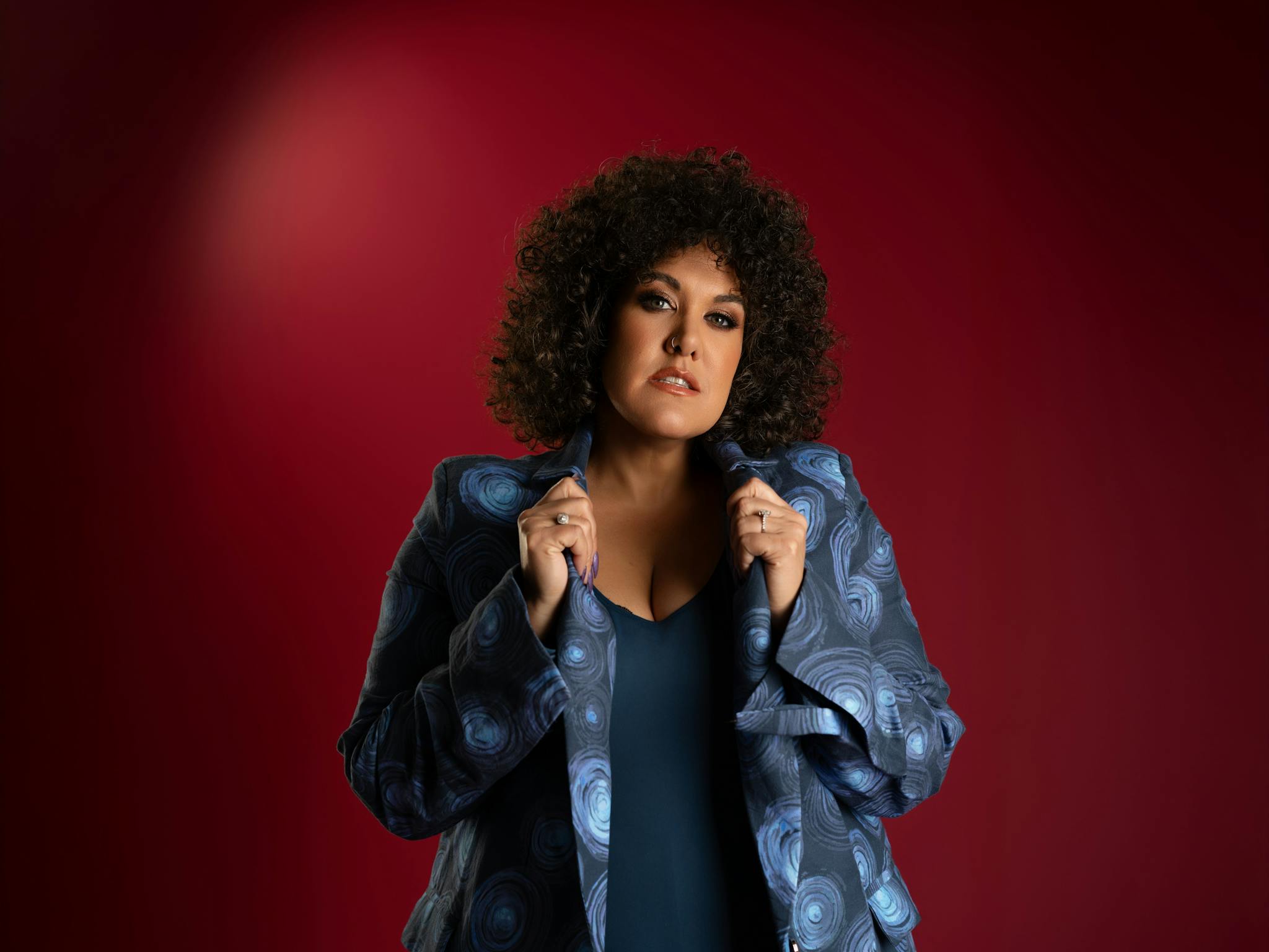 Casey with curly hair and hands on collar of shirt Casey with curly hair and hands on collar of shirt