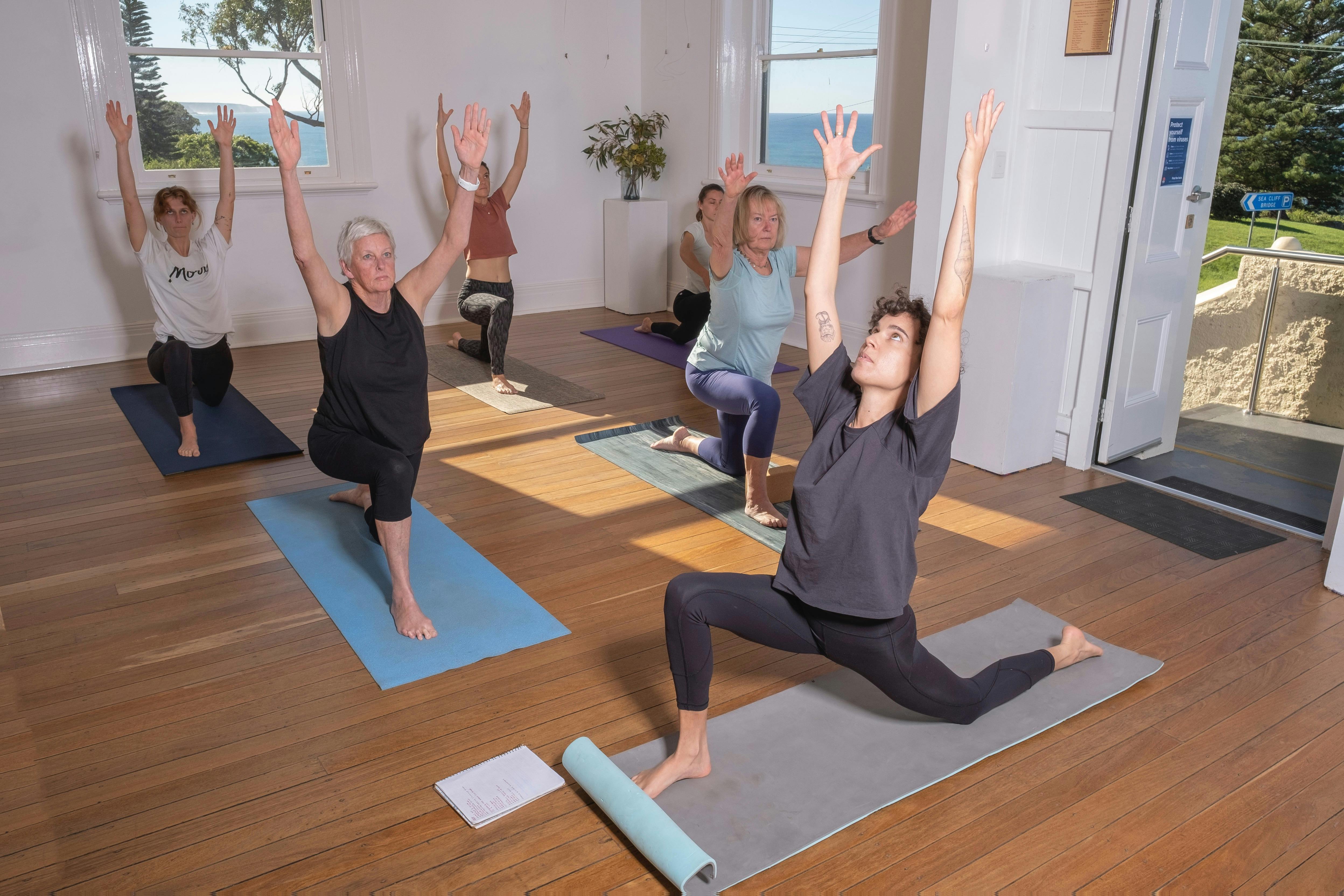 海を見下ろす日当たりの良いホールで女性のグループがヨガを練習します