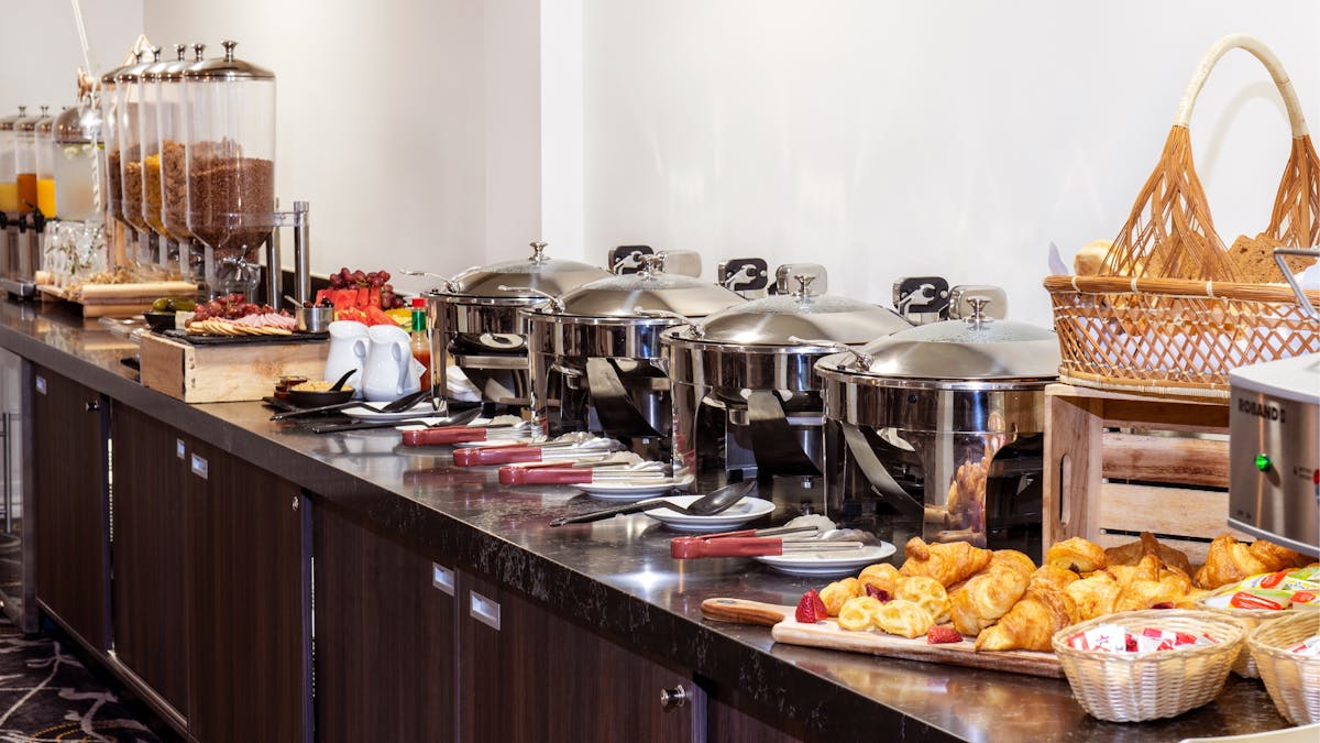 Buffet Breakfast Station featuring a variety of dishes and appliances along the bench