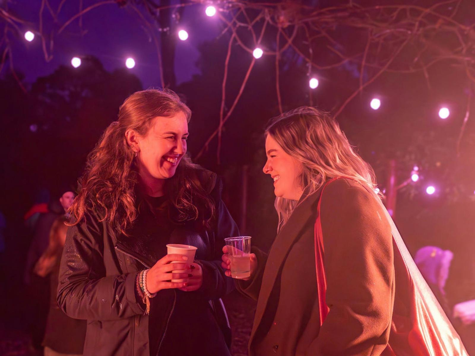 Two friends smile together over a mulled wine