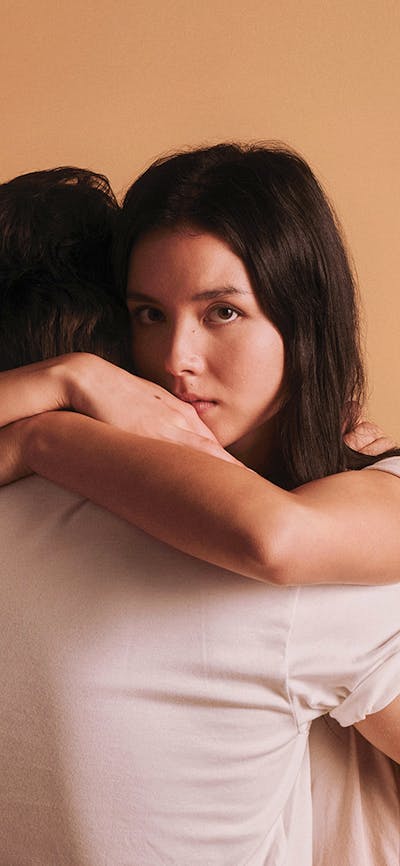 A woman is hugging another person who is facing away from the camera