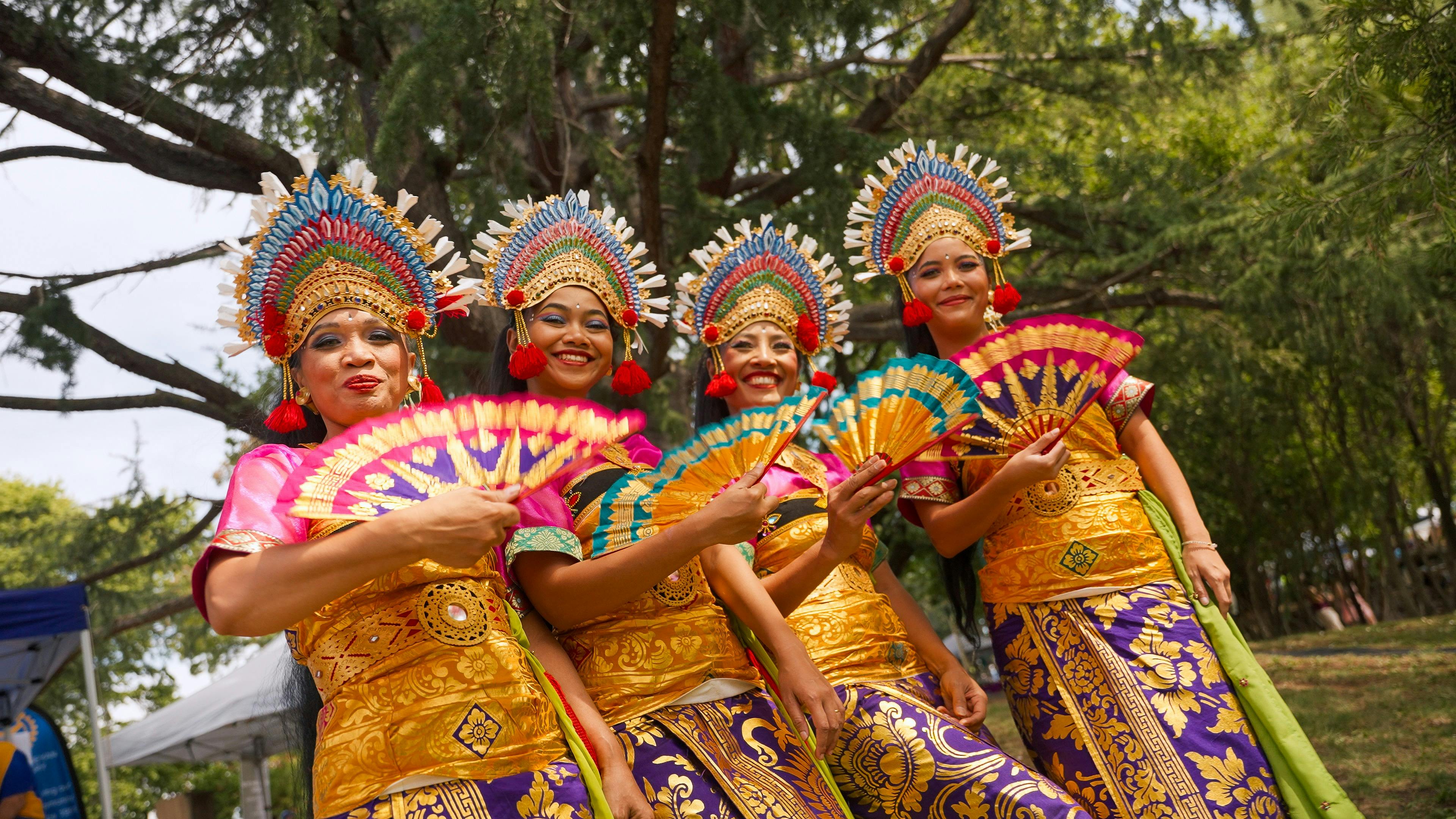 Performers in costume posing with fans and smiling