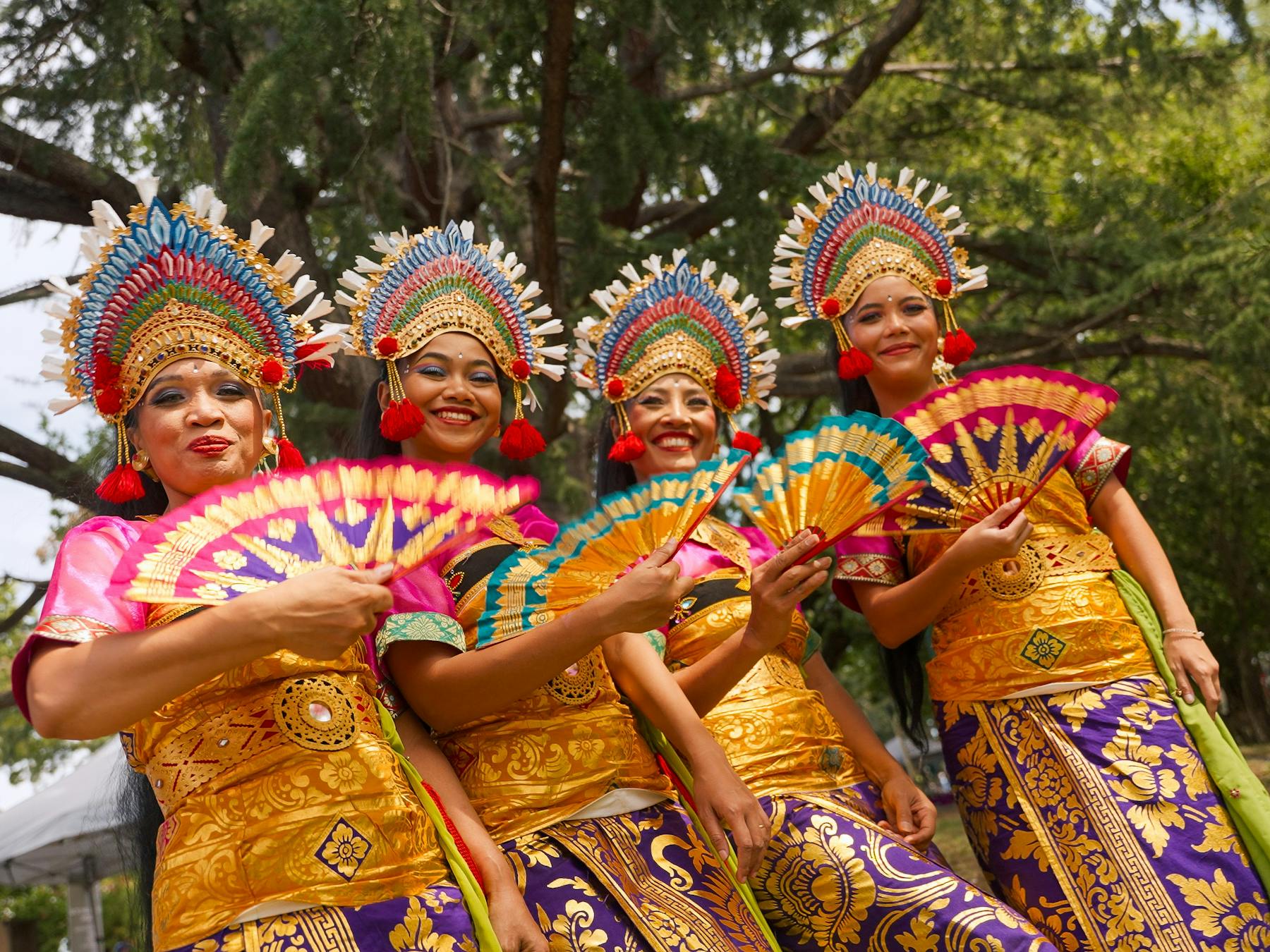 Performers in costume posing with fans and smiling