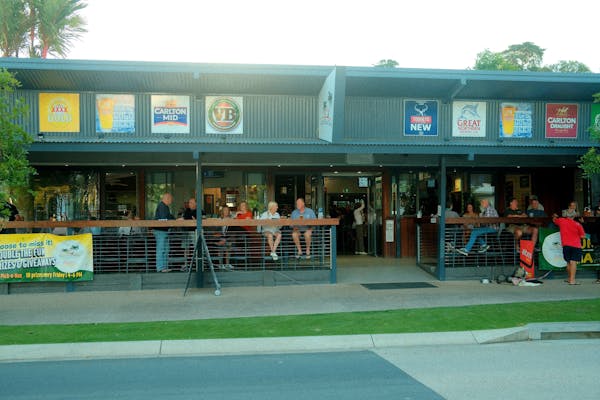 Street view of Mission Beach Tavern with guests on the front deck in the evening