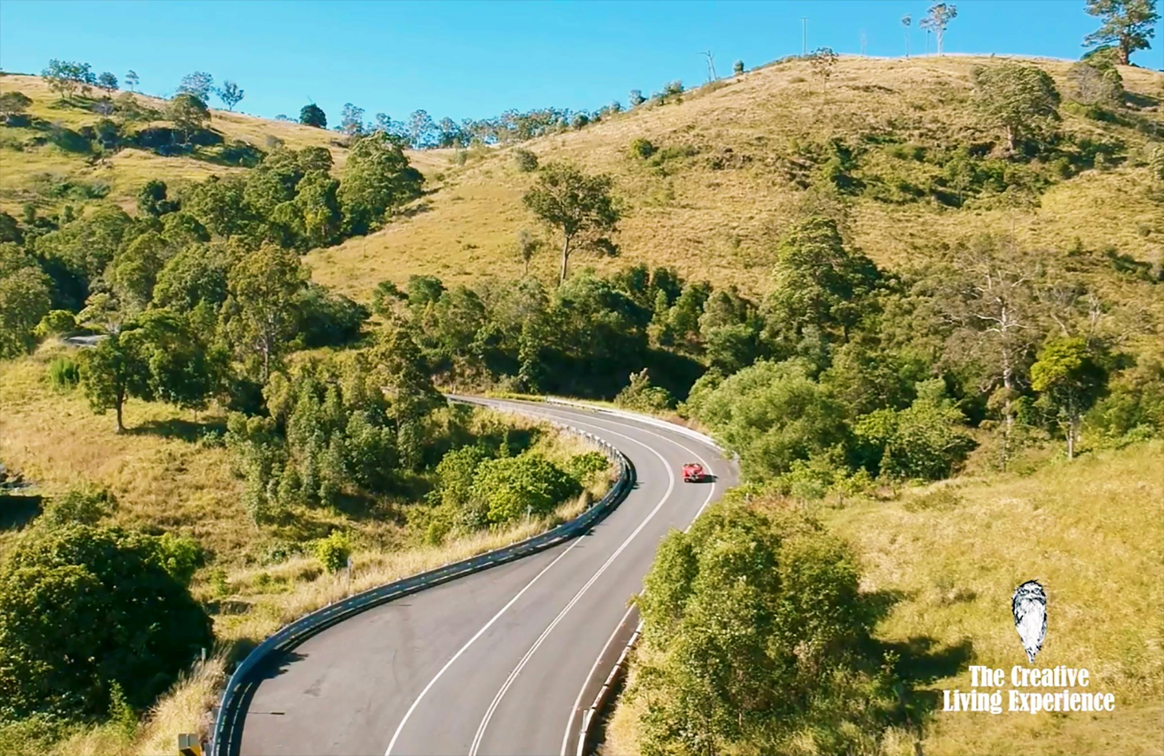 red car driving windy country road