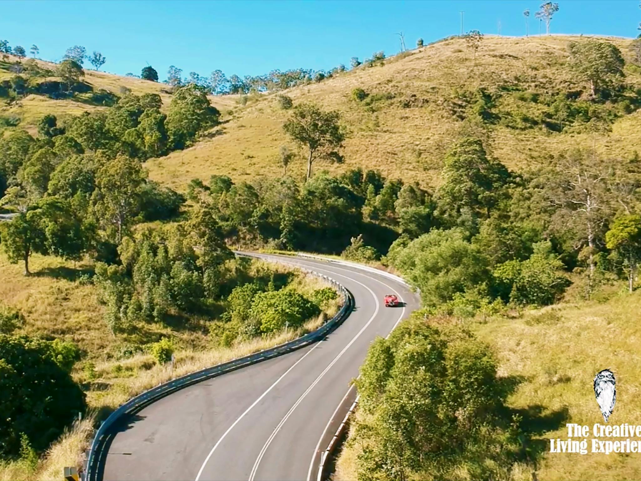 red car driving windy country road