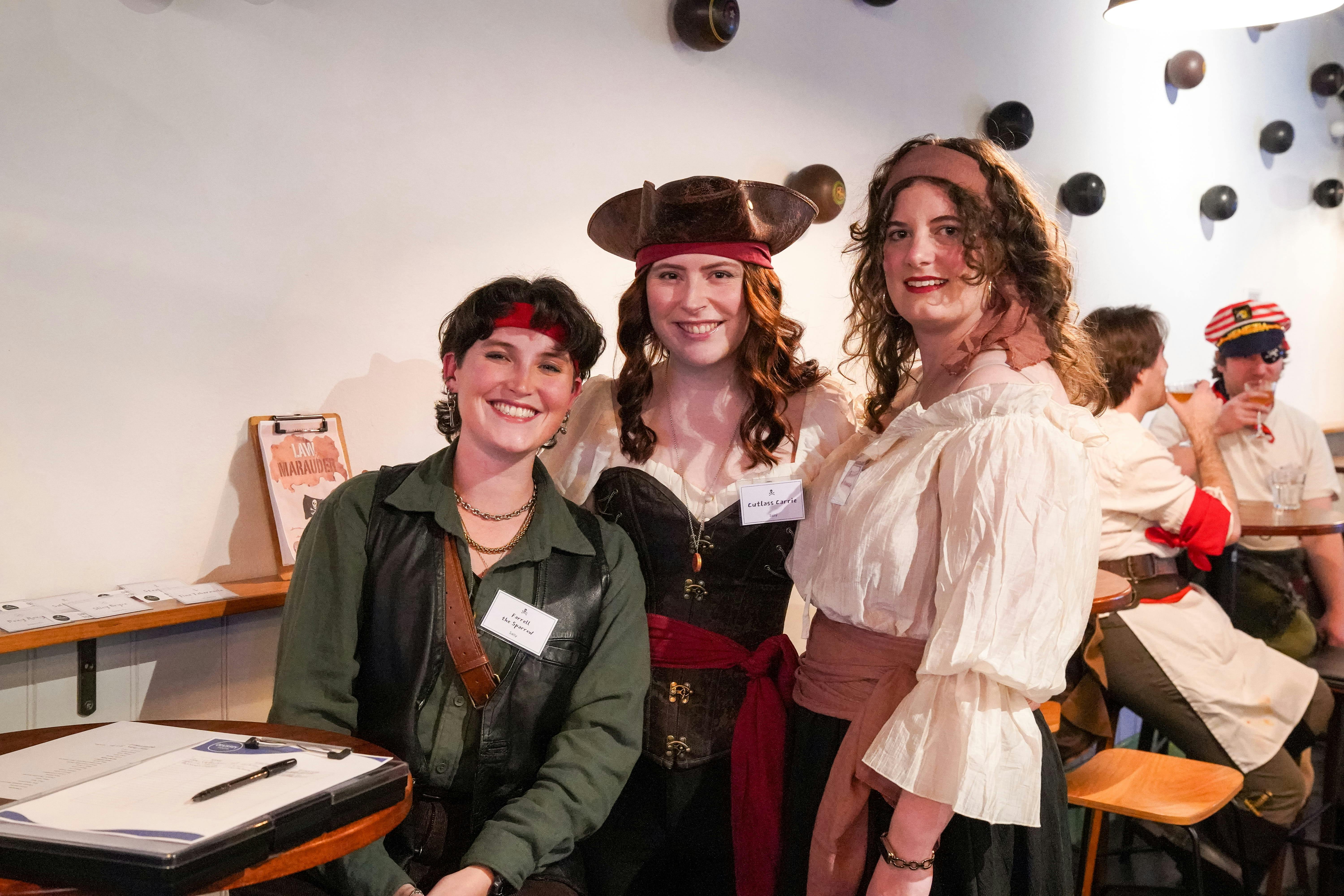 Three people in pirate outfits smile at the camera