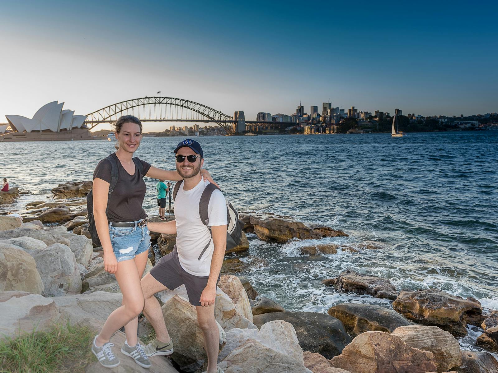 A young couple on the harbours edge with Opera House and Bridge in background