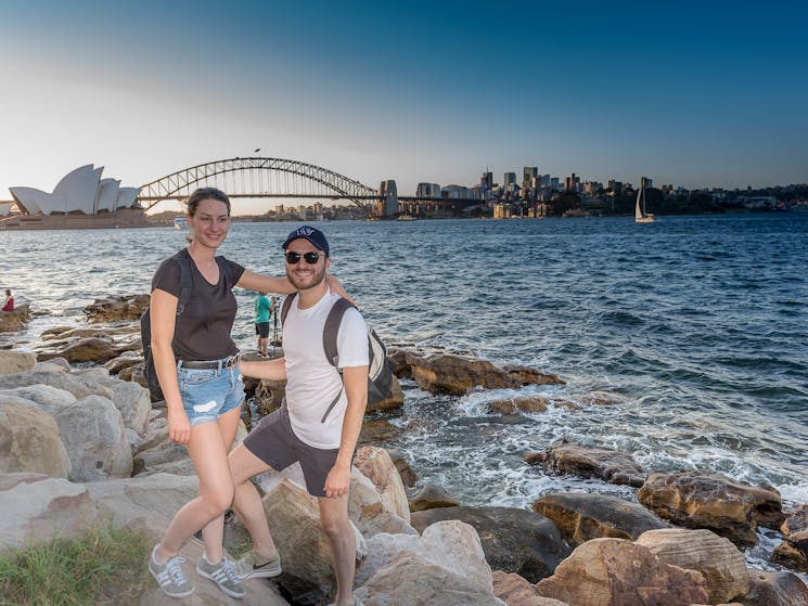 A young couple on the harbours edge with Opera House and Bridge in background
