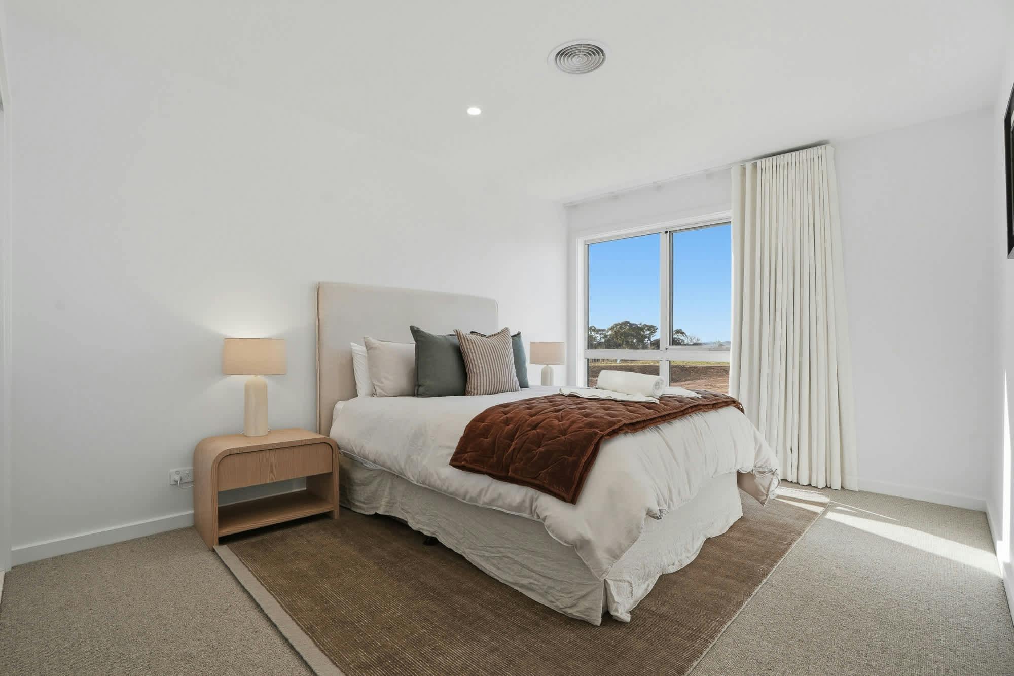 Bedroom with queen beds, rug, side tables, lamps and curtains