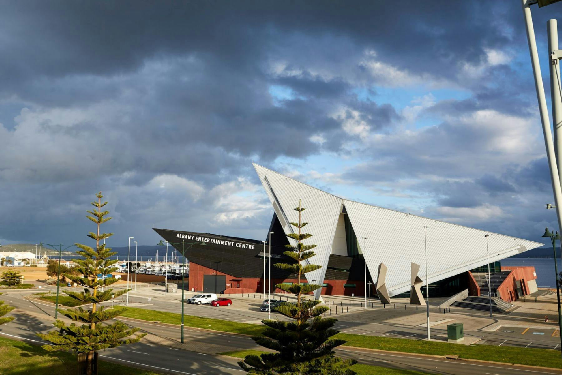 Building with triangular roof line with thundery clouds and view to water