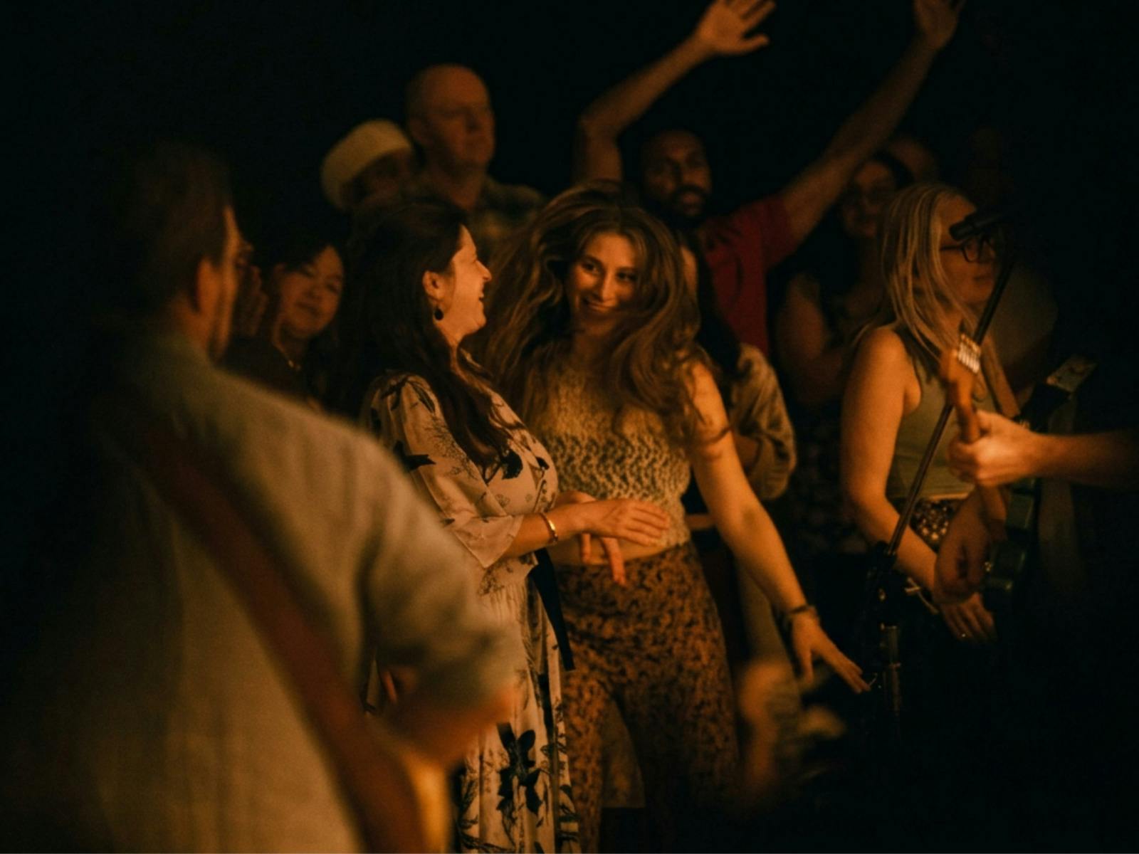 2 women dancing and smiling in a crowd