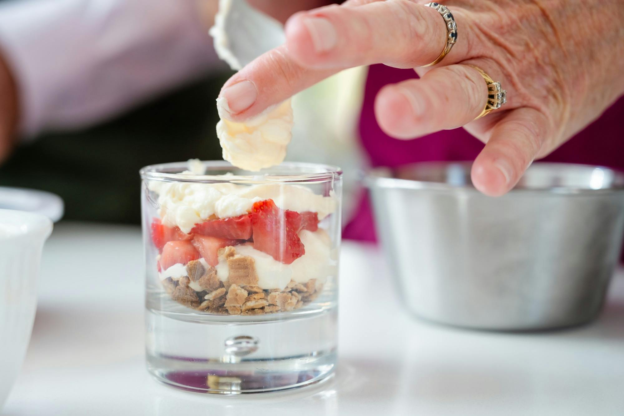 Chef adding the finishing touch to a layered dessert in a glass