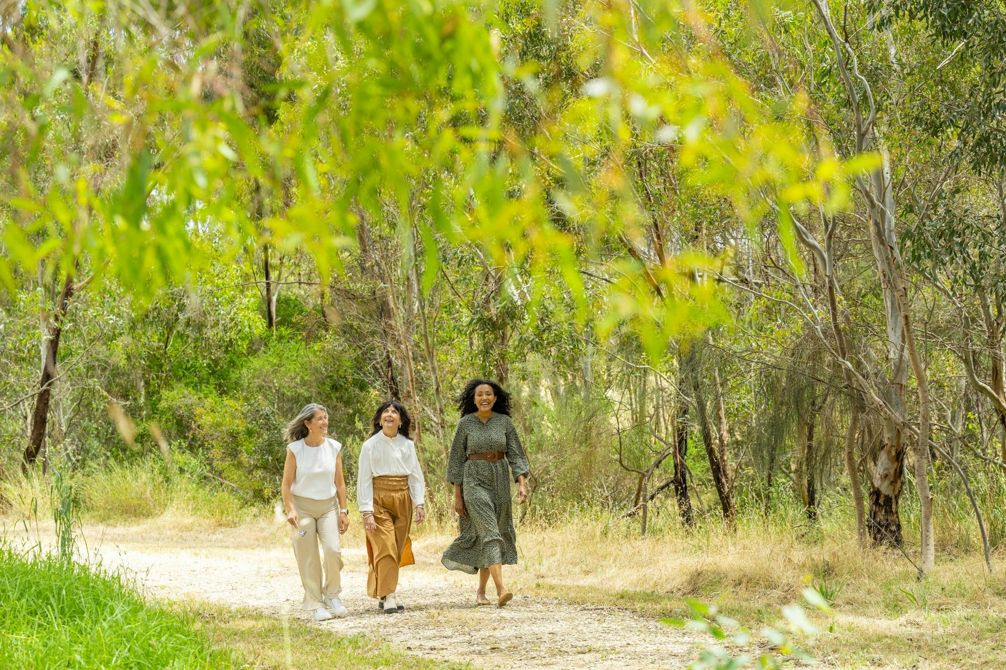 A group of women walking on a trail surrounded by trees