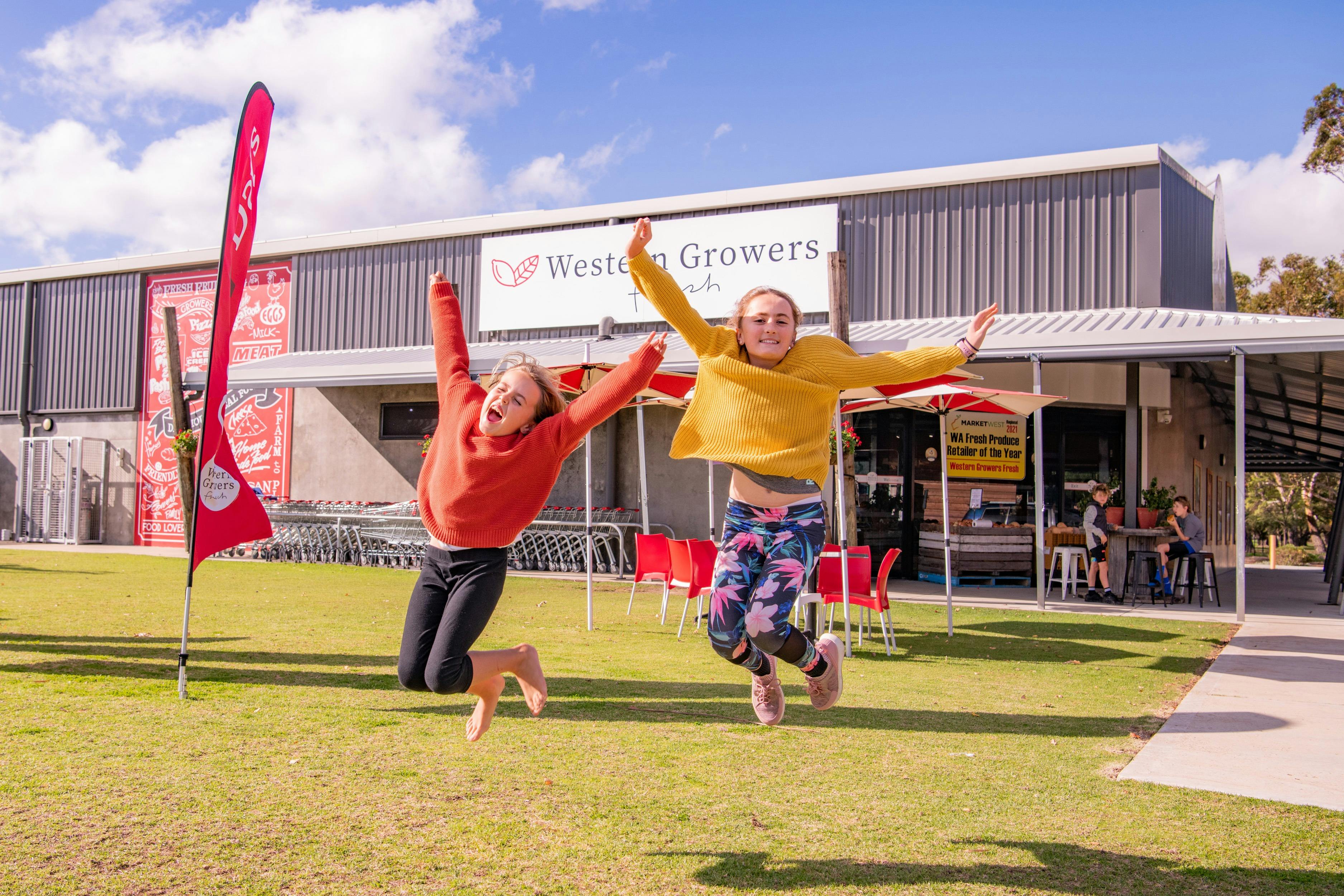 2 children jumping for joy on a lawn