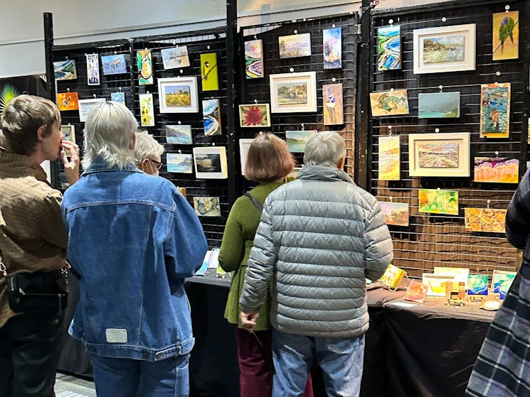 Patrons admiring the artwork in the mini's category at the Art Show.