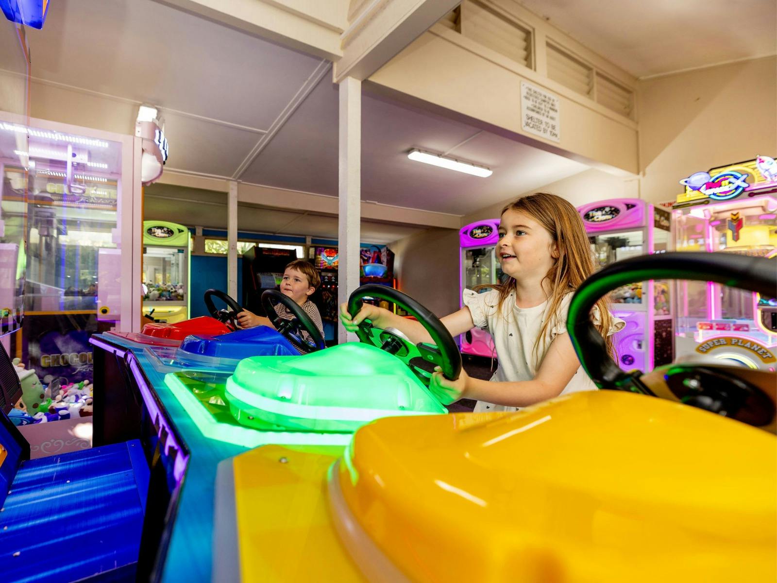Two children playing a colourful car racing arcade game