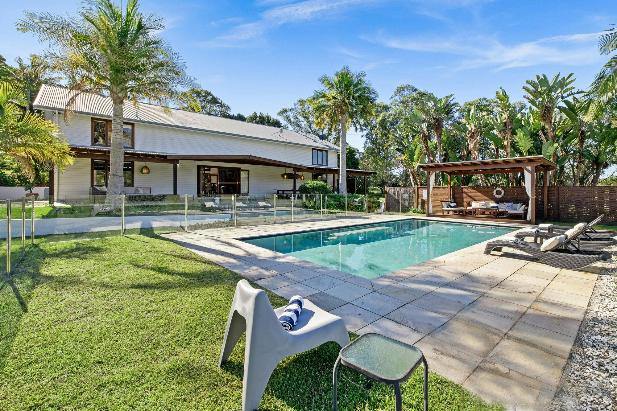 Private expansive pool surrounded by a landscaped garden with lounge chairs and sunny open spaces