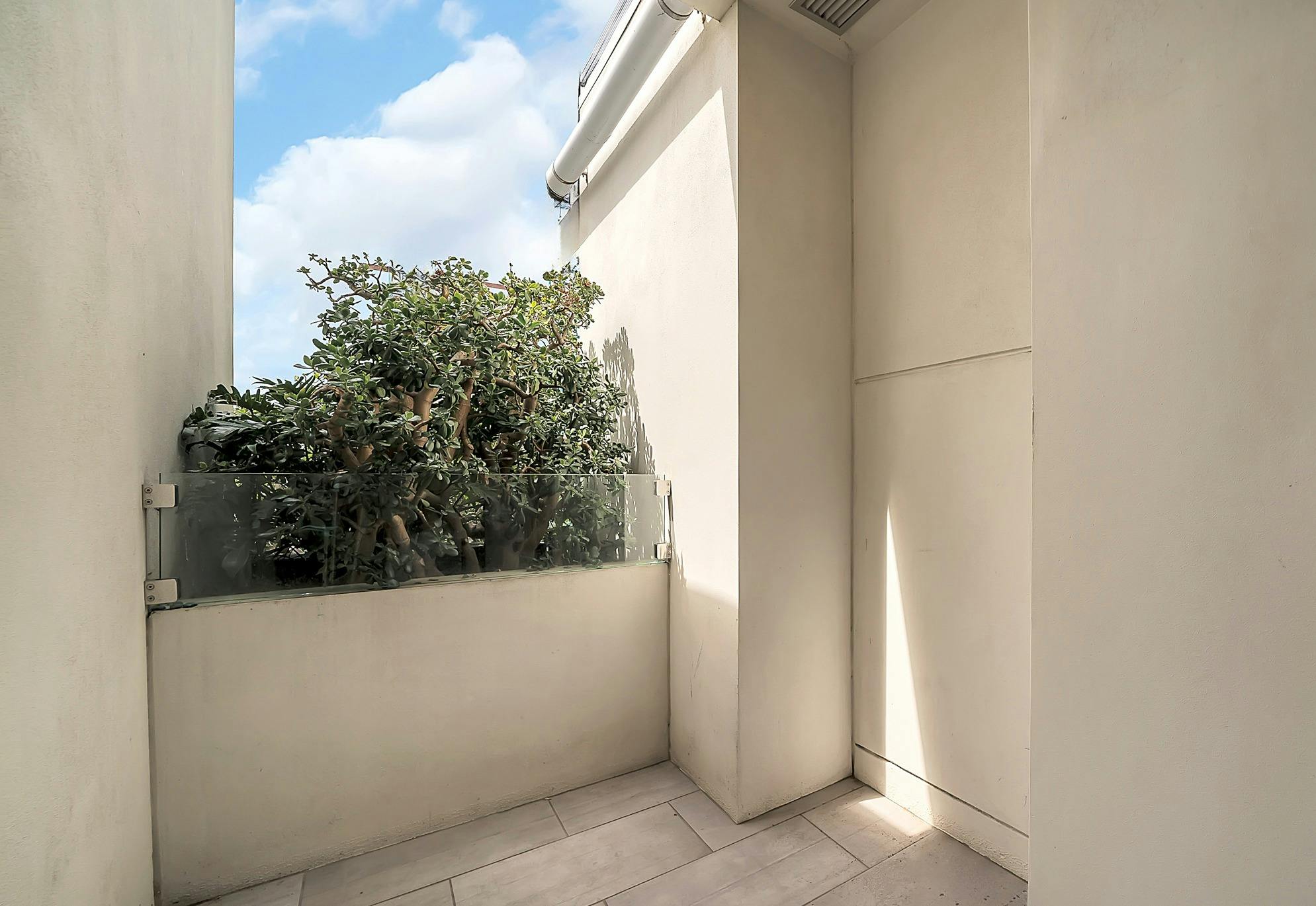 Private balcony with greenery and clear sky views.