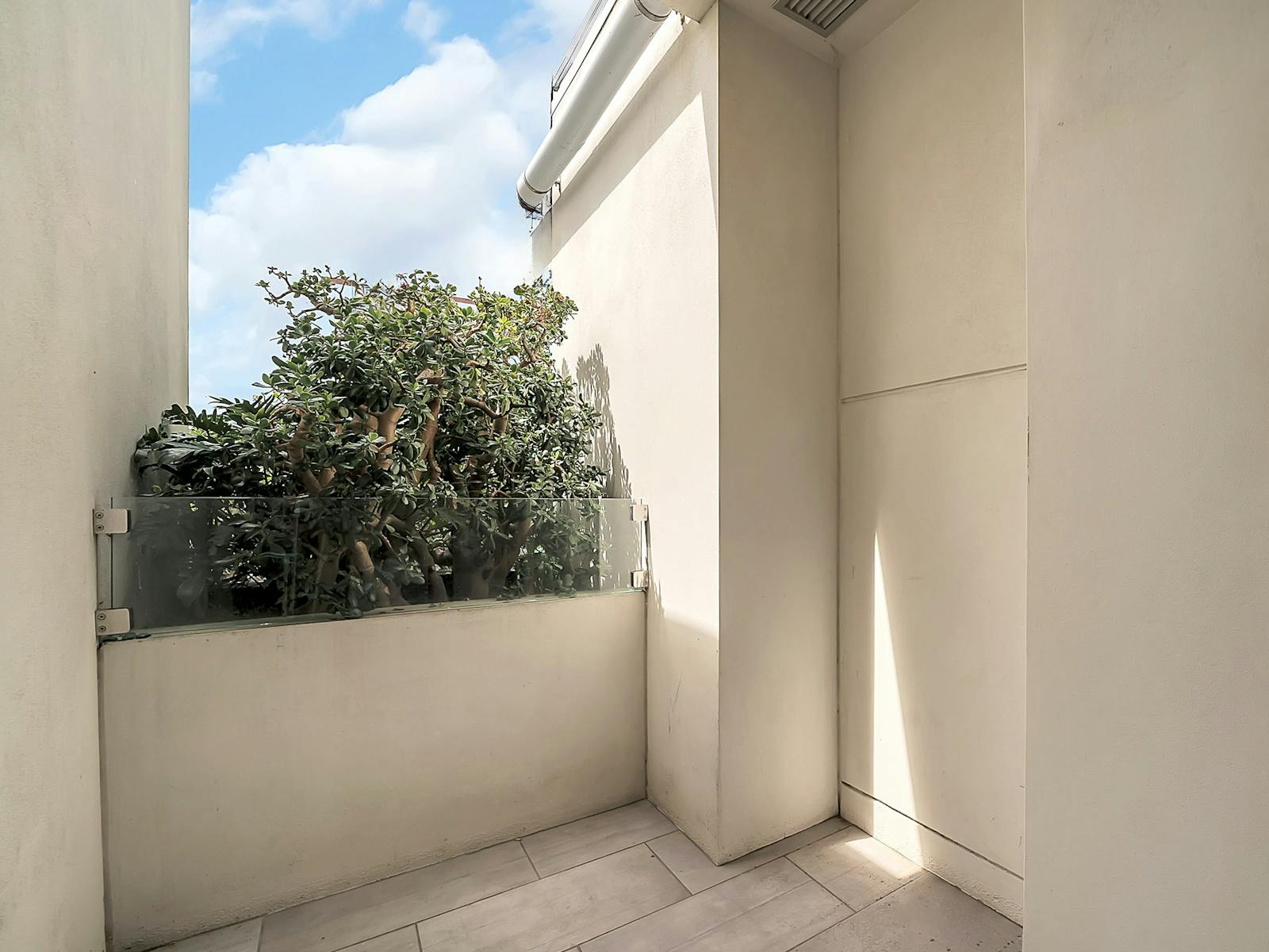 Private balcony with greenery and clear sky views.