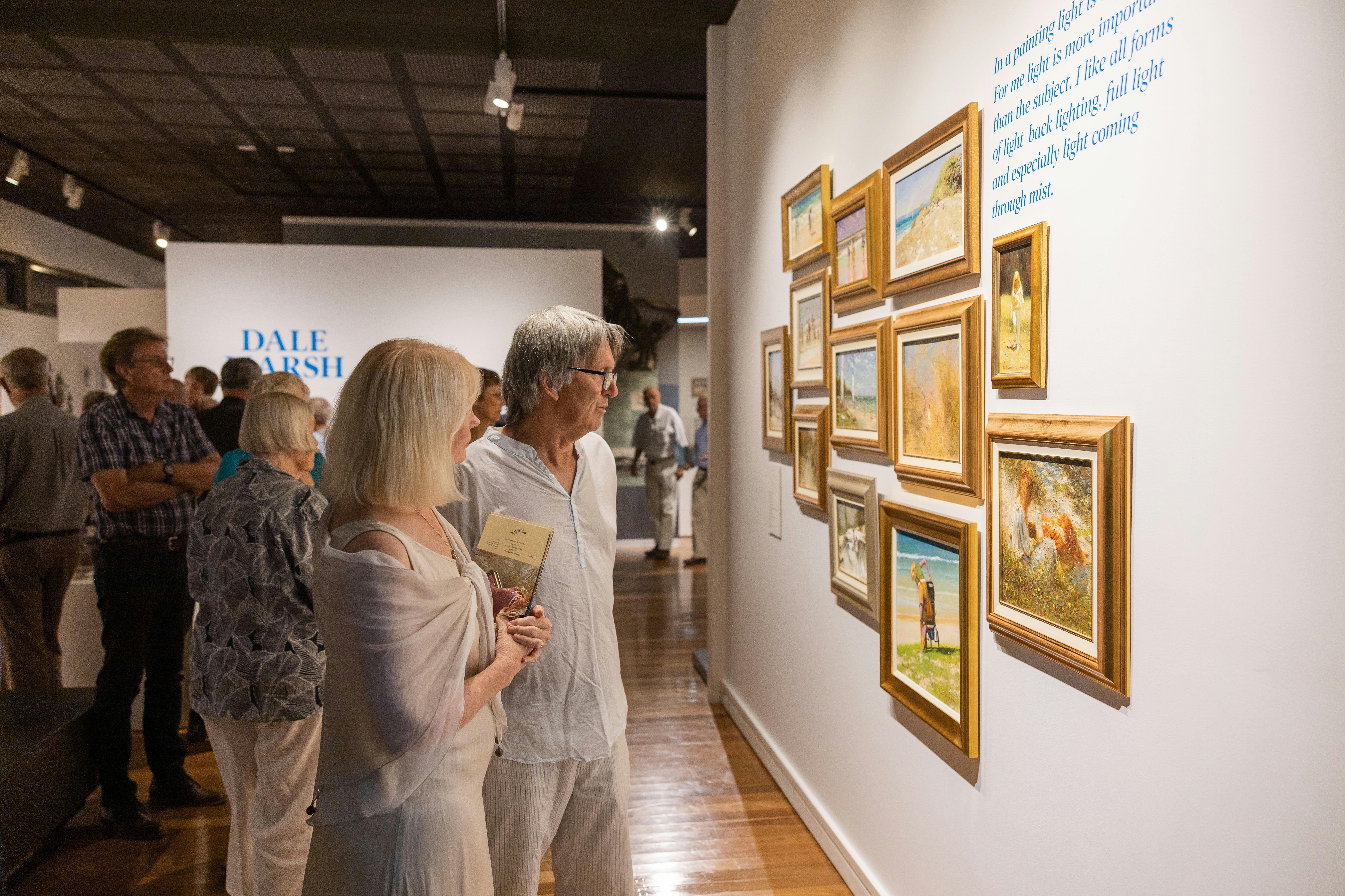 Man and woman looking at art in frames on the wall