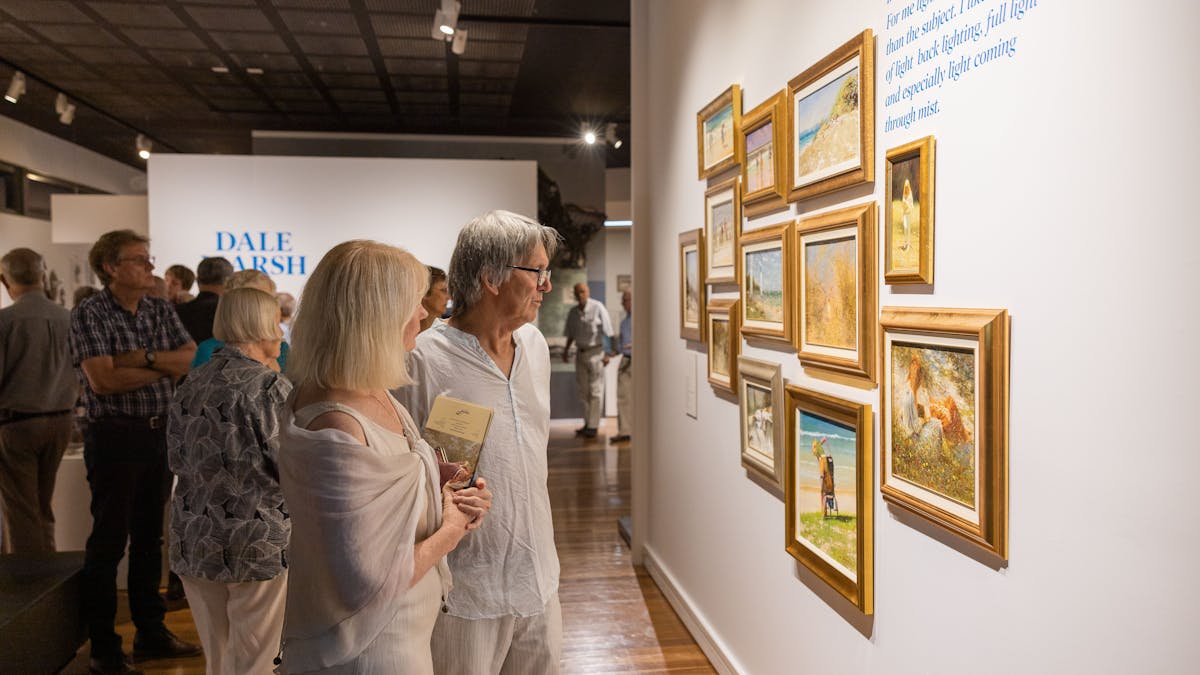 Man and woman looking at art in frames on the wall