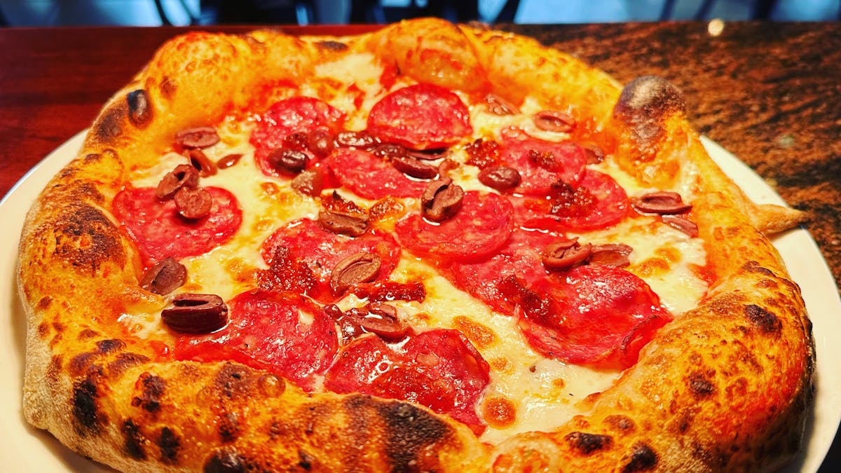Cozy Italian restaurant with wood-fired pizzas and warm, inviting atmosphere.b