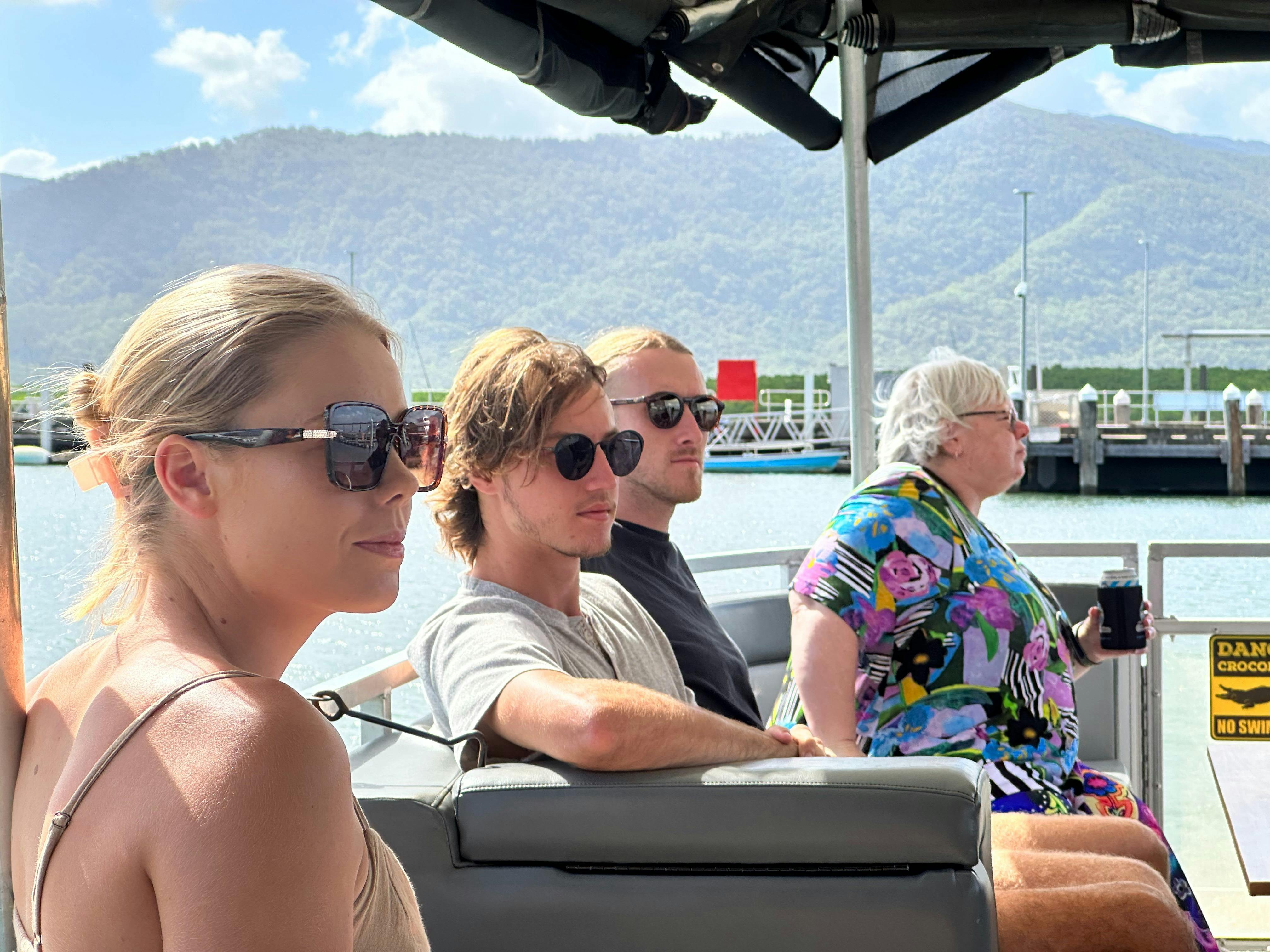 Group of young travellers listening as the skipper talks about local wildlife on the Trinity Inlet