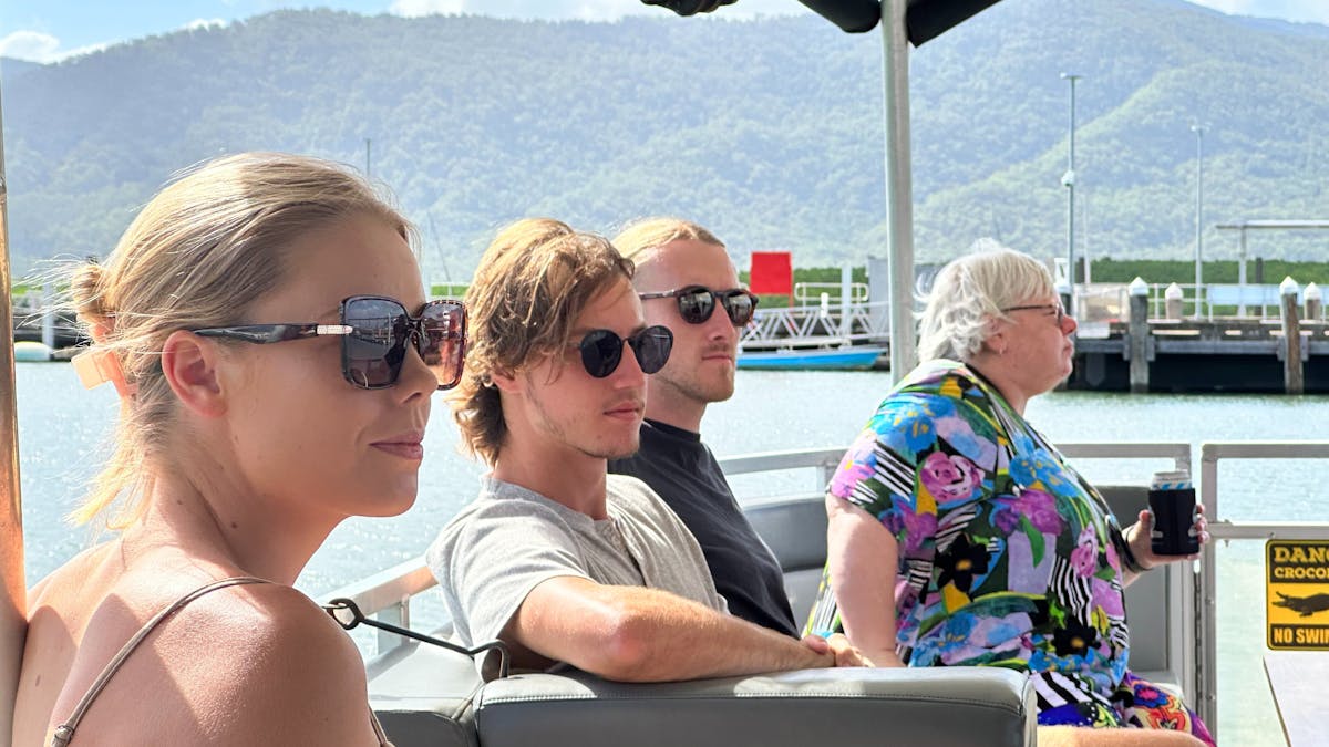 Group of young travellers listening as the skipper talks about local wildlife on the Trinity Inlet