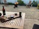 A wooden outdoor setting with wine and grazing platter. In the background a fire pit crackles away.