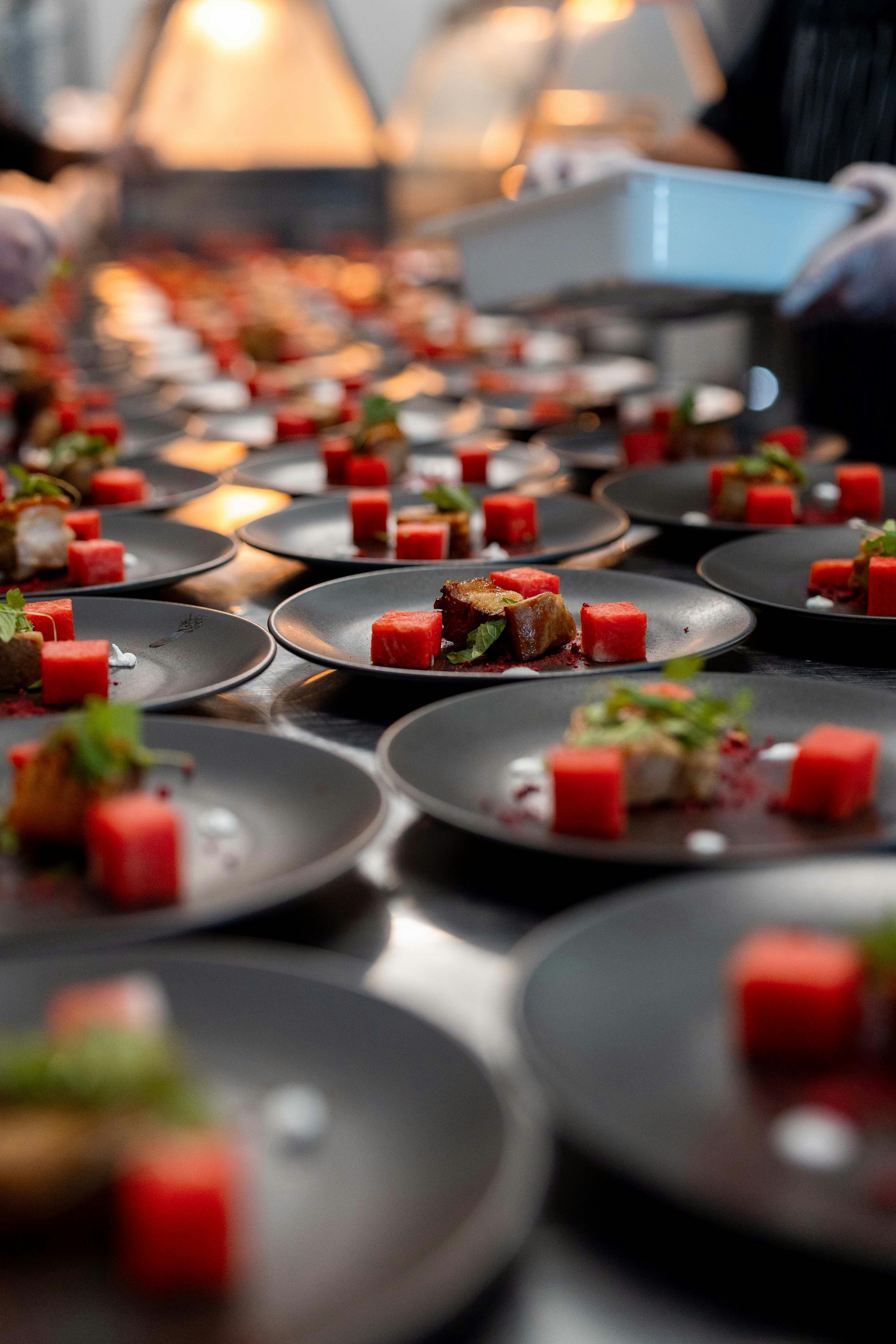 Multiple plated dishes arranged on a preparation bench under warm lighting.