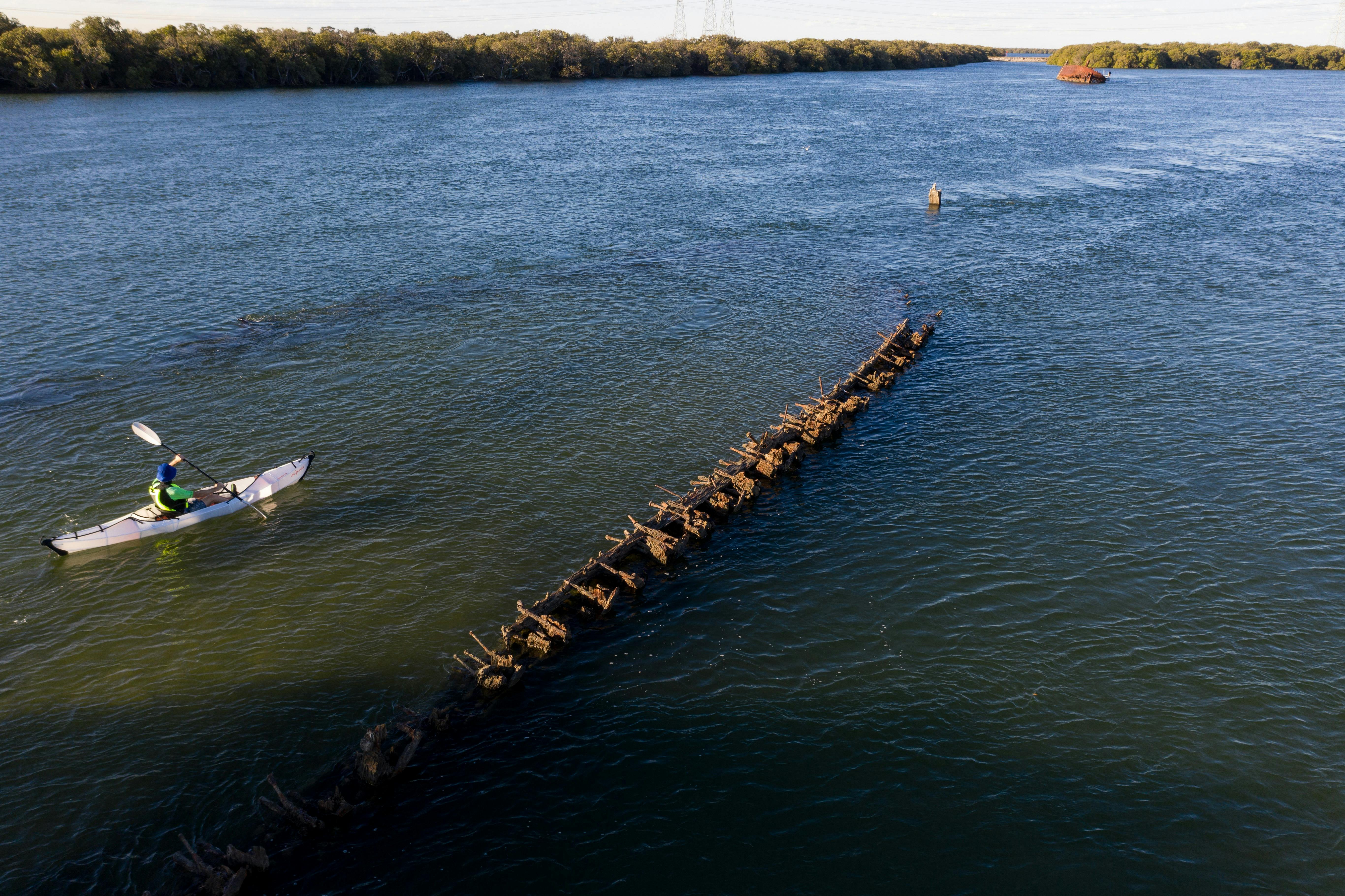 Single kayaker paddling over old shipwreck