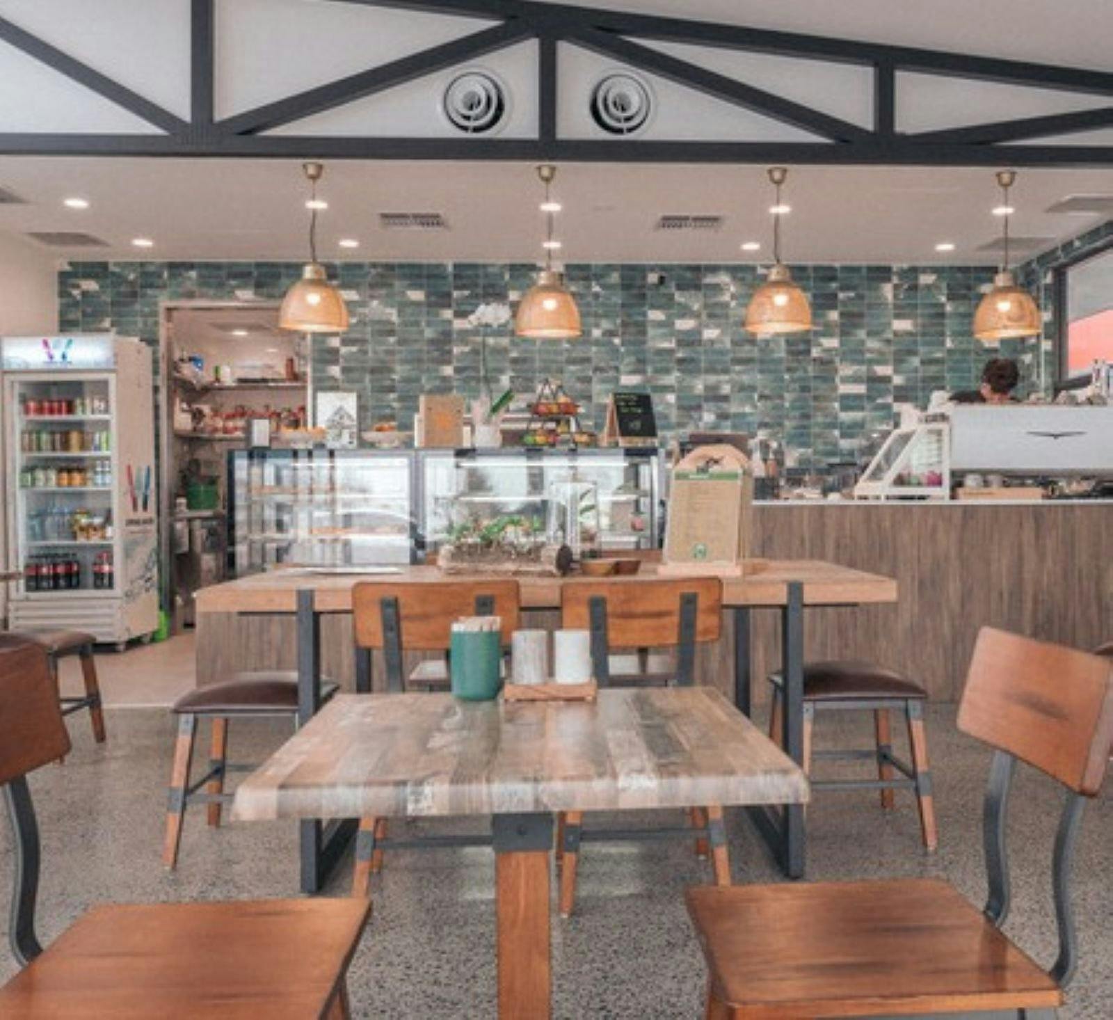 Interior view of cafe with table and chairs, display fridges and counter
