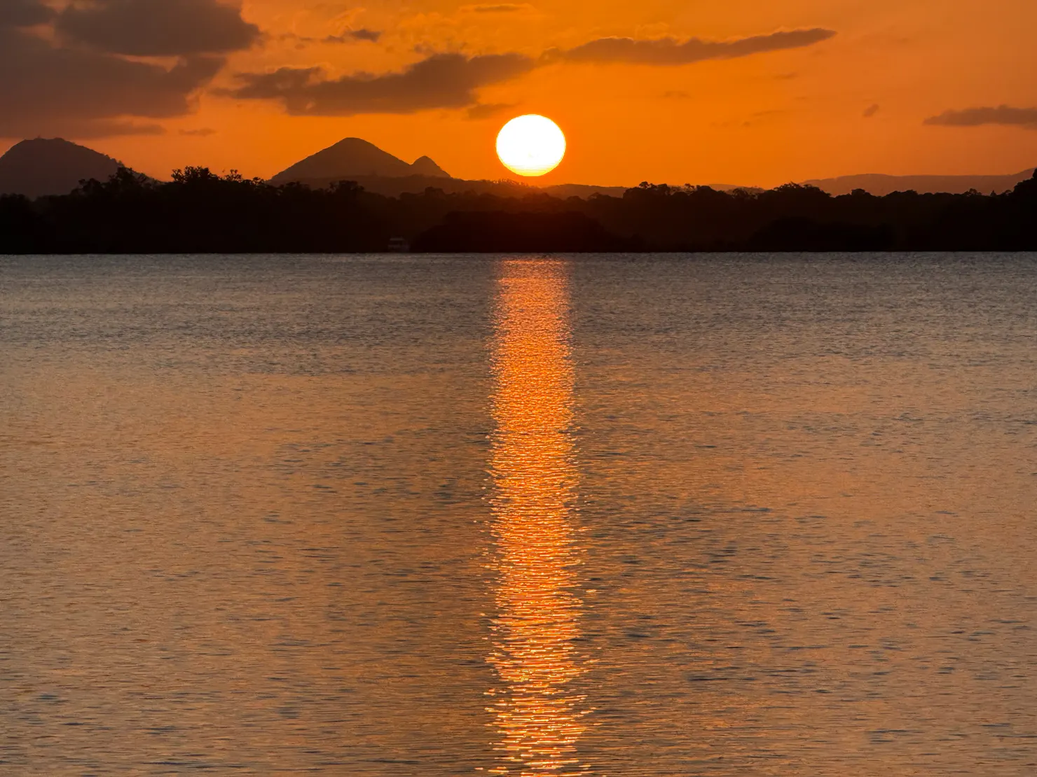 sunset over the glasshouse mountain on a sunset tour onboard caloundra charters