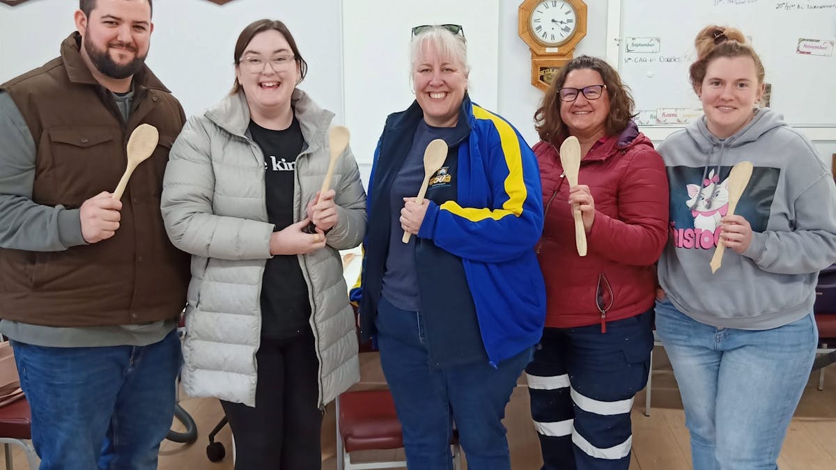 5 people standing holding wooden spoons