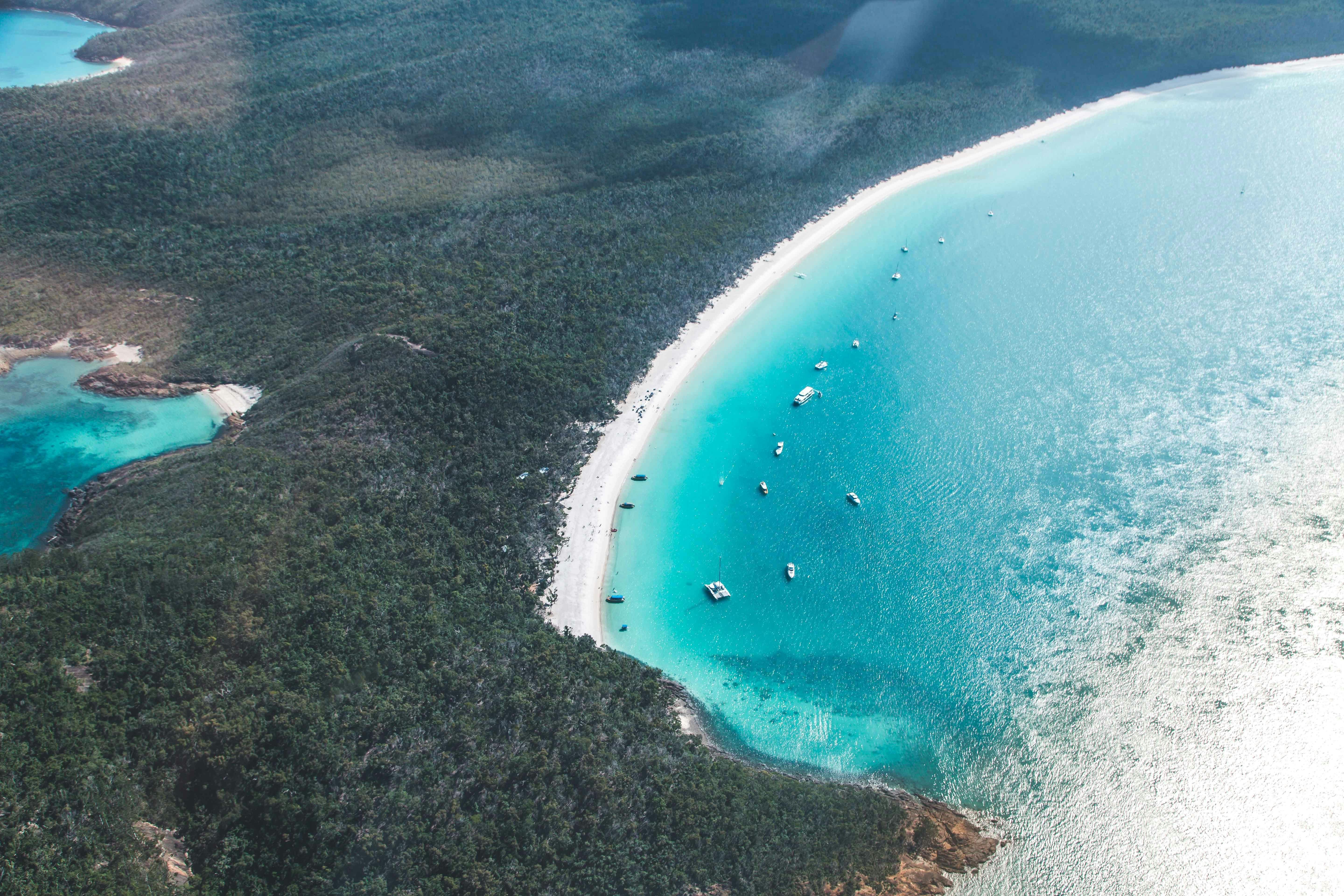 Aerial view of the long stretch of Whitehaven Beach surrounded by blue waters and national park