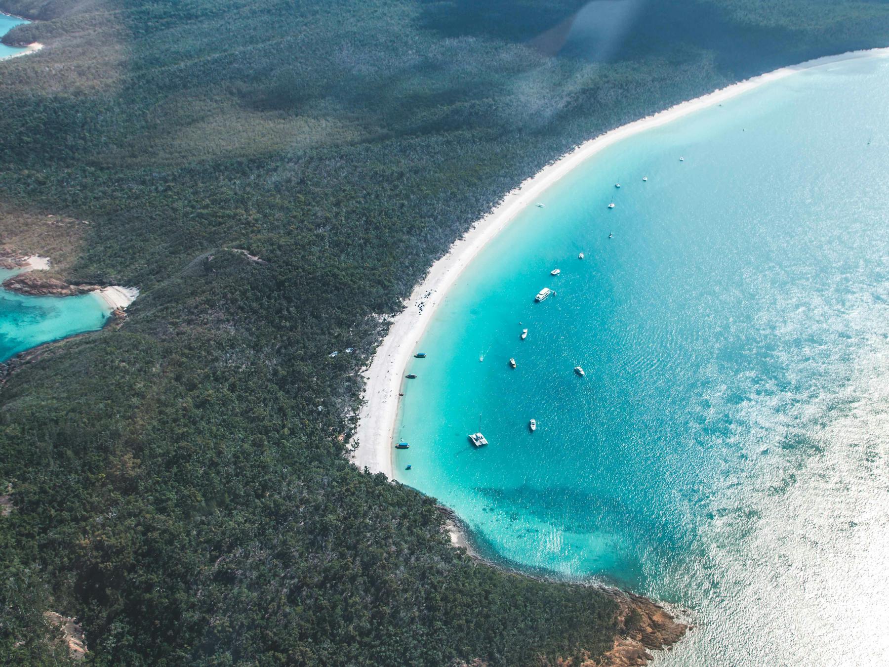 Aerial view of the long stretch of Whitehaven Beach surrounded by blue waters and national park