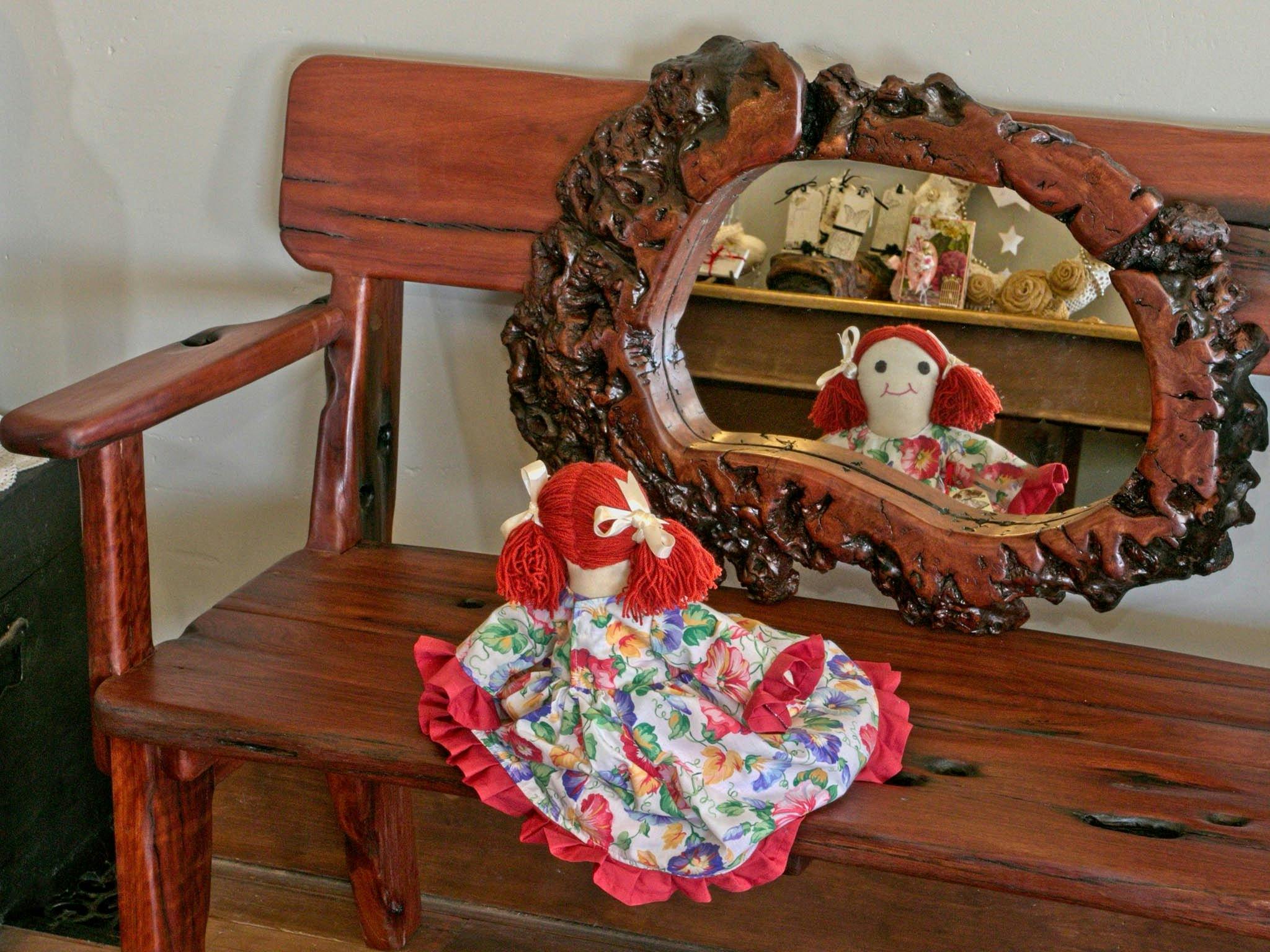 Rag doll on wooden bench reflected in burl mirror