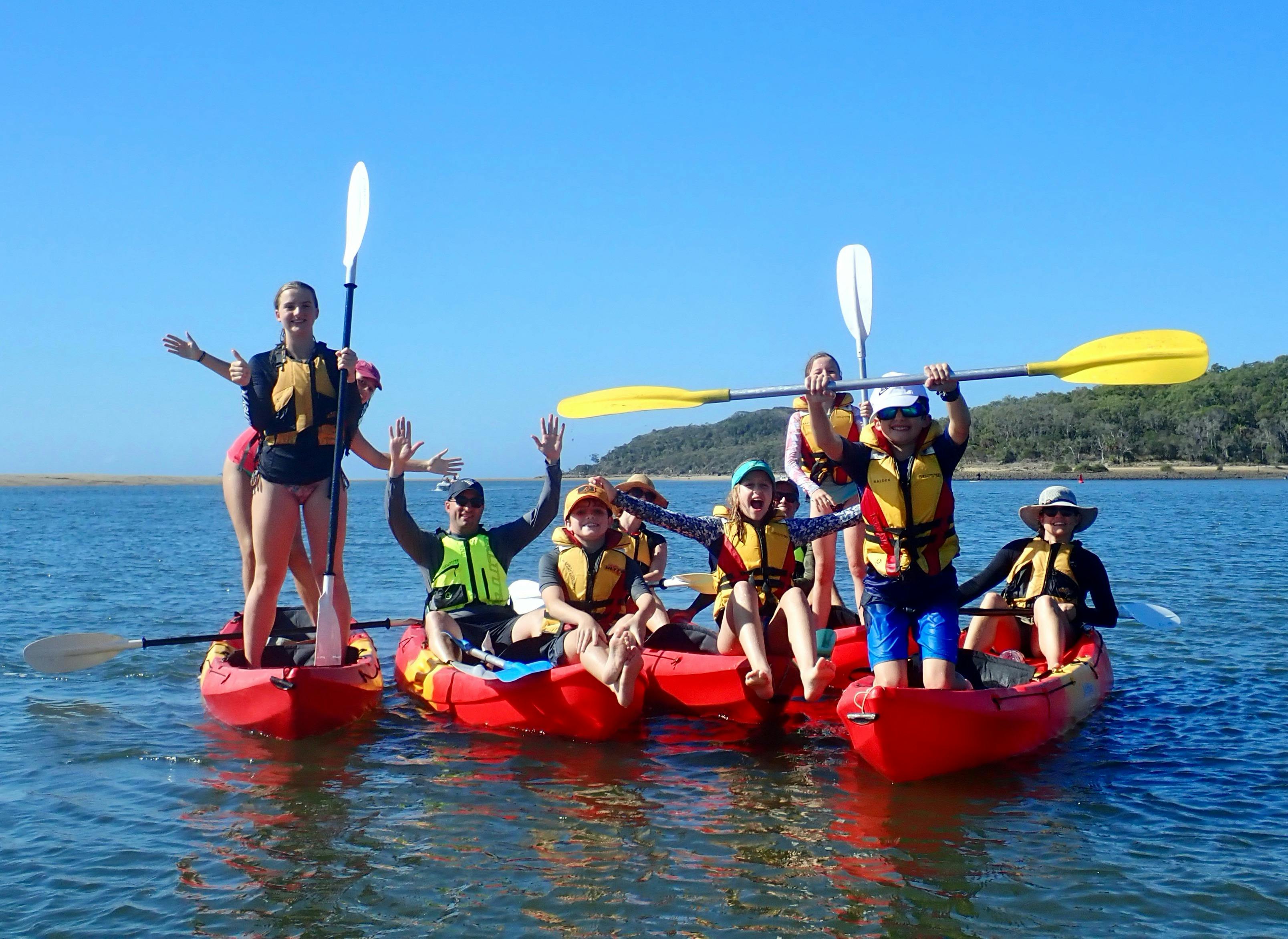 A couple of families posing on kayaks with 1770 Liquid Adventures in Queensland