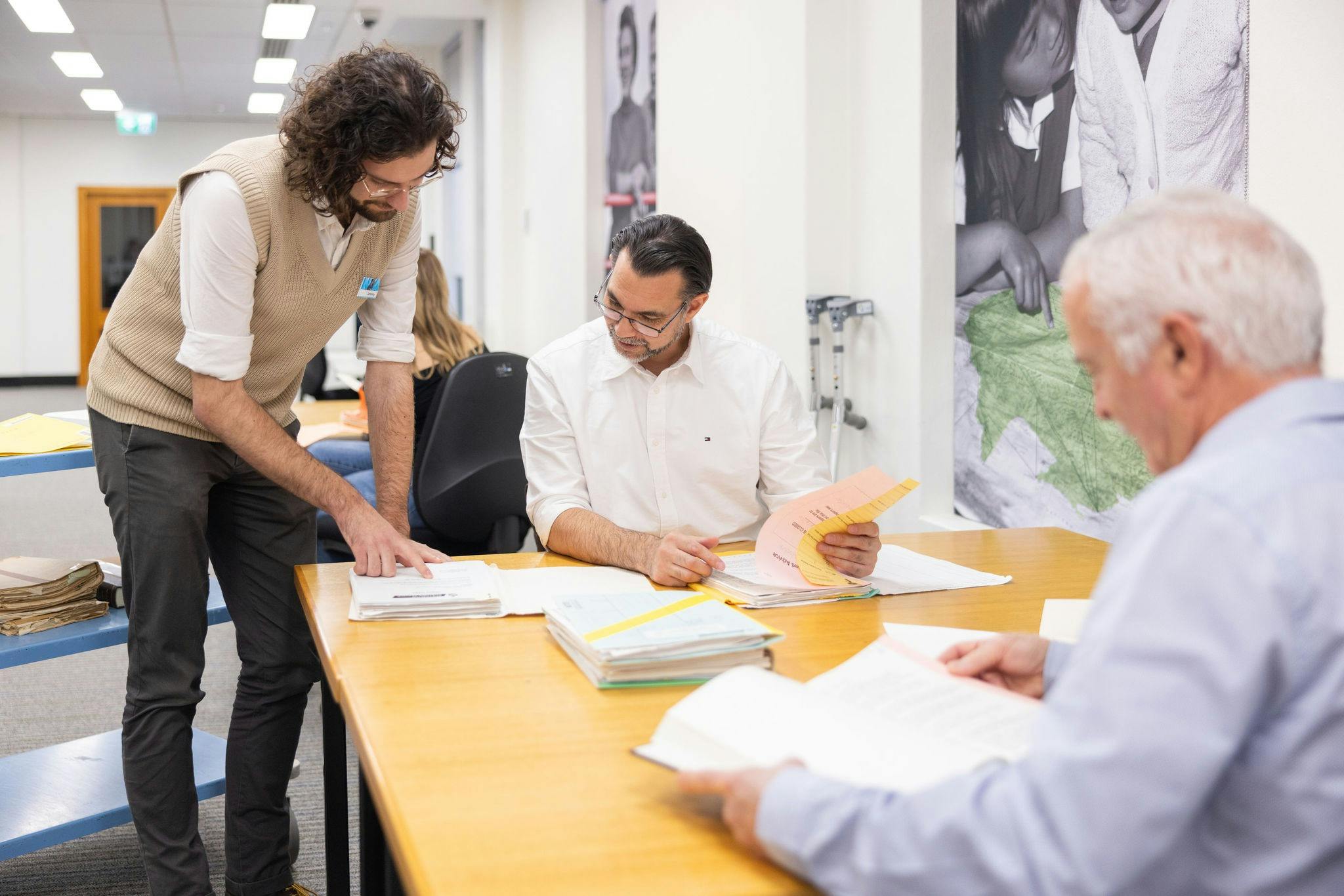 Assistant helping explain records to two people in Research Centre.