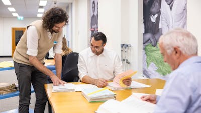 Assistant helping explain records to two people in Research Centre.