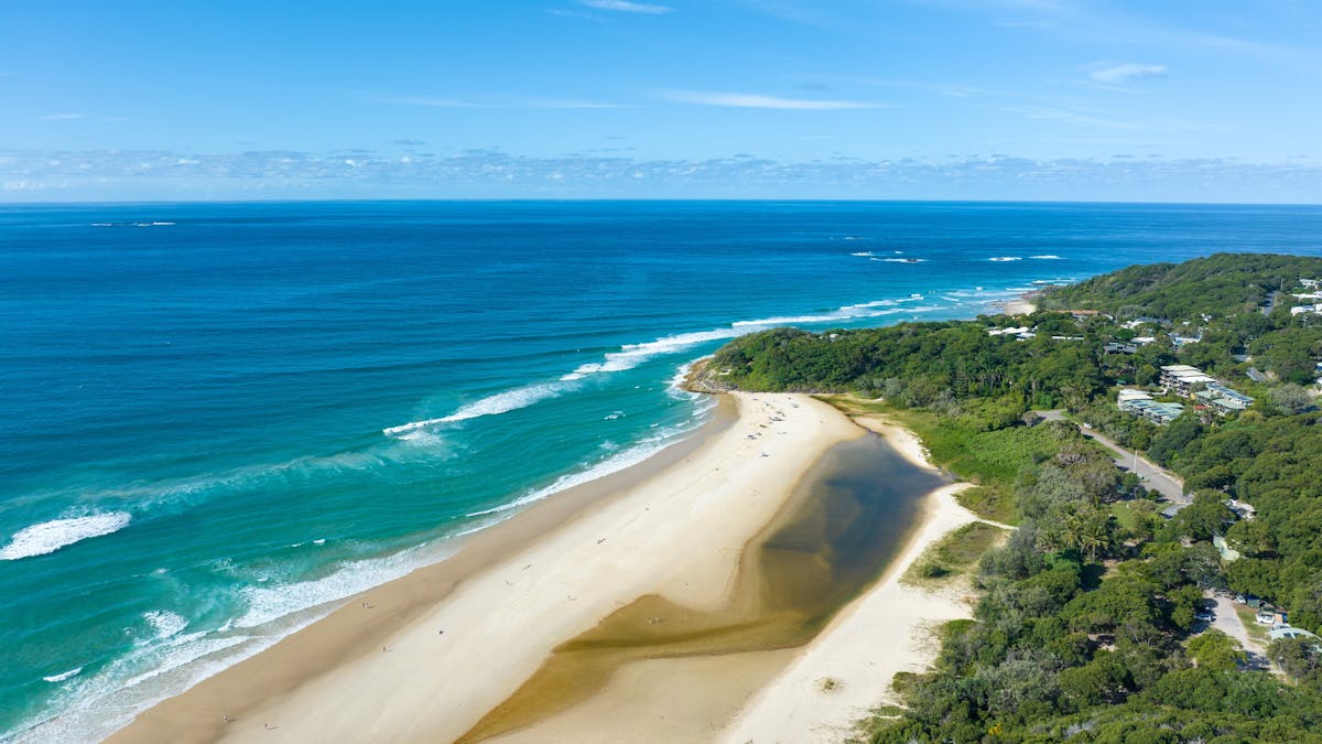 Drone view - a Cylinder beach bordered by blue ocean and coastal vegetation on Stradbroke Island