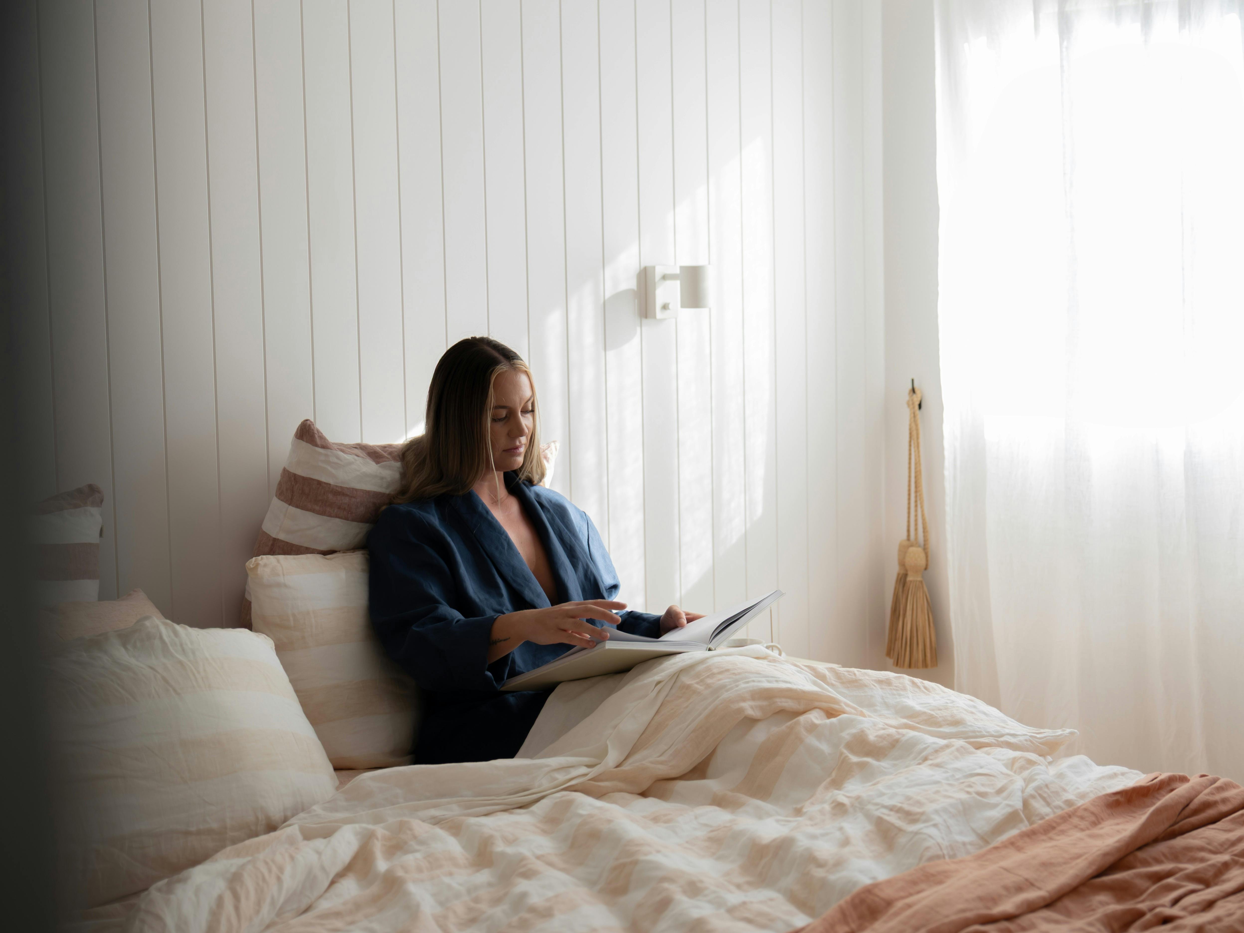 Female guest reading in sun-filled bedroom