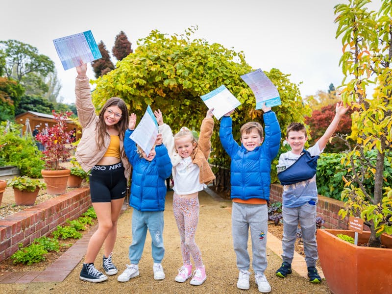 Children in the Botanical Gardens with clue sheets and hands in the air