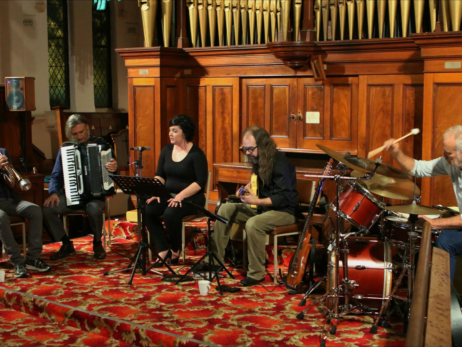 Trumpeter, accordionist, singer guitarist and drummer in front of organ