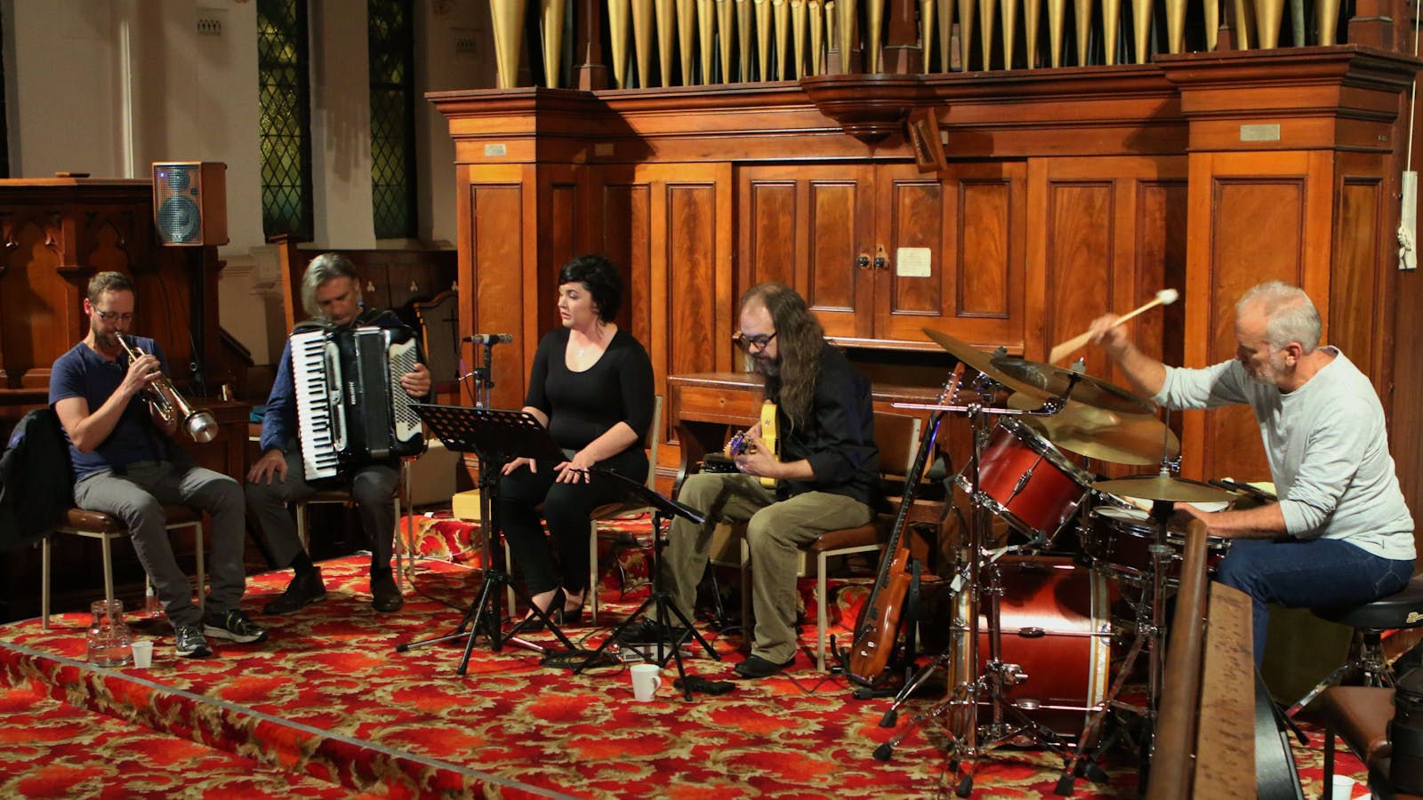 Trumpeter, accordionist, singer guitarist and drummer in front of organ