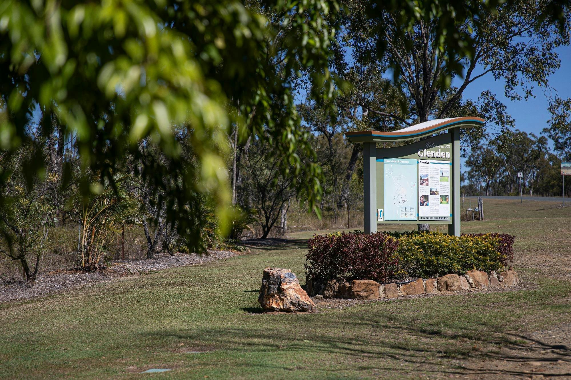 Welcome sign in a garden bed surrounded by rocks and shrubs