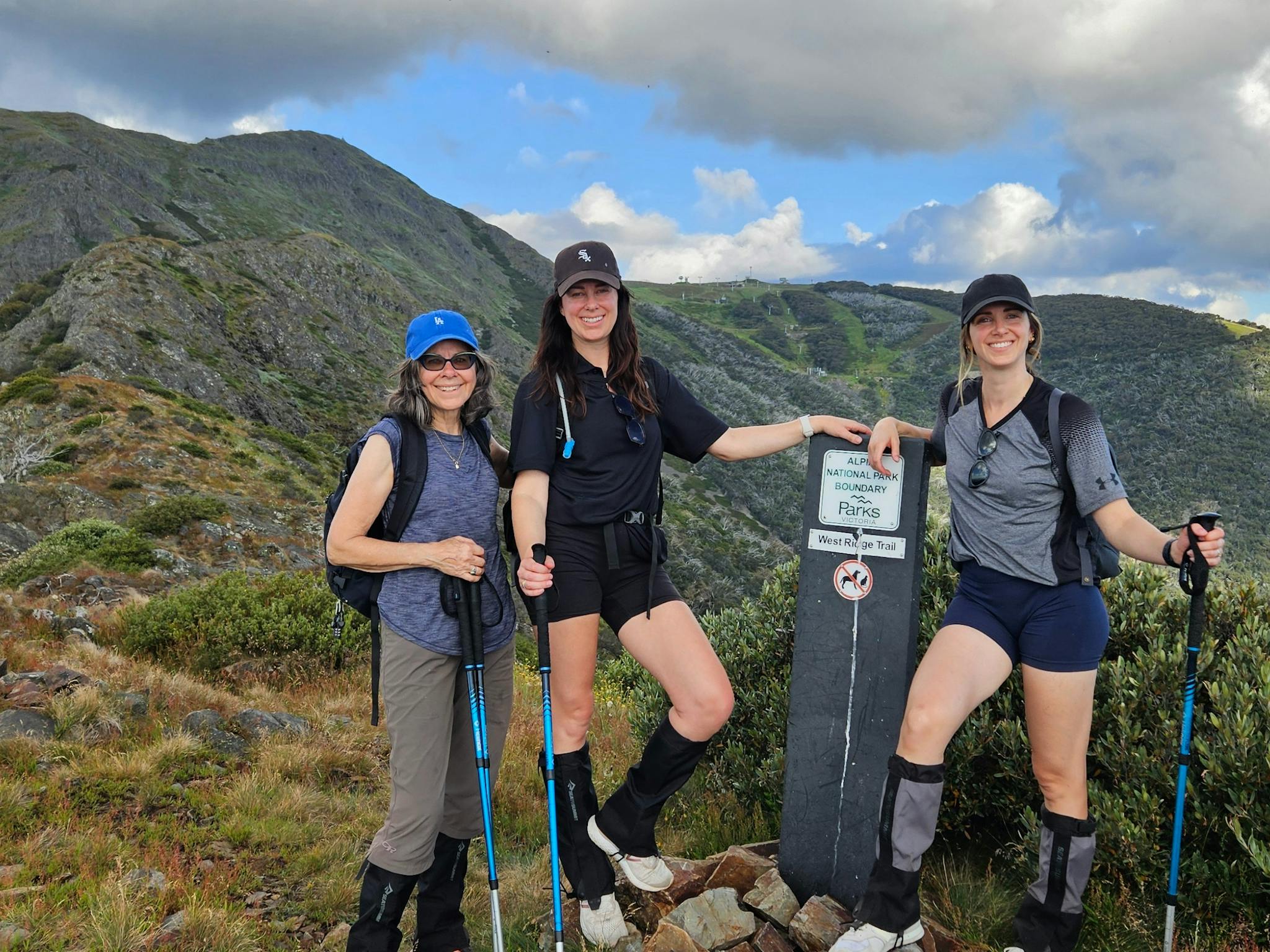 Clients at the West Ridge sign with summit of Mt Buller in the background